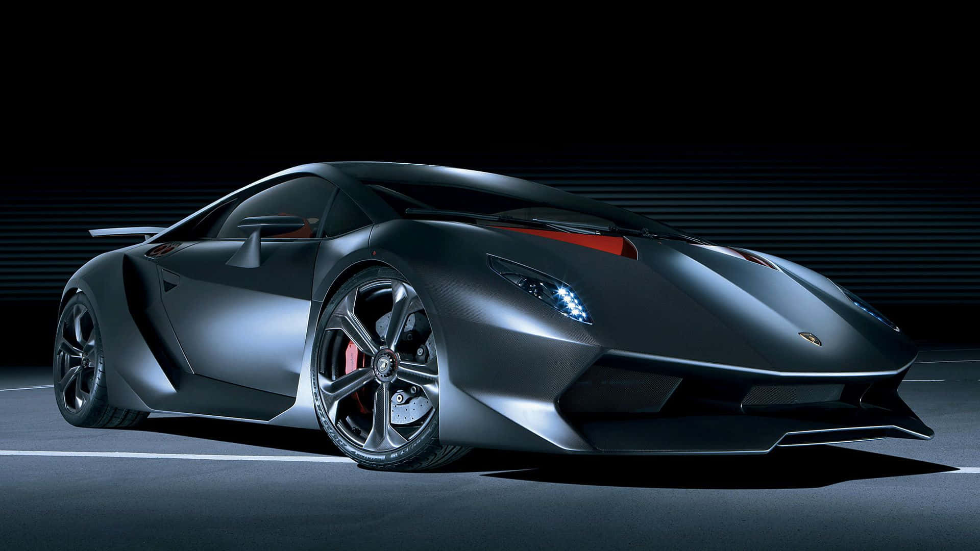 Lamborghini Sesto Elemento 桌布 壁紙 — 一輛時尚的啞光黑色藍寶堅尼跑車，帶有紅色點綴，在黑暗道路上的工作室燈光下閃耀。