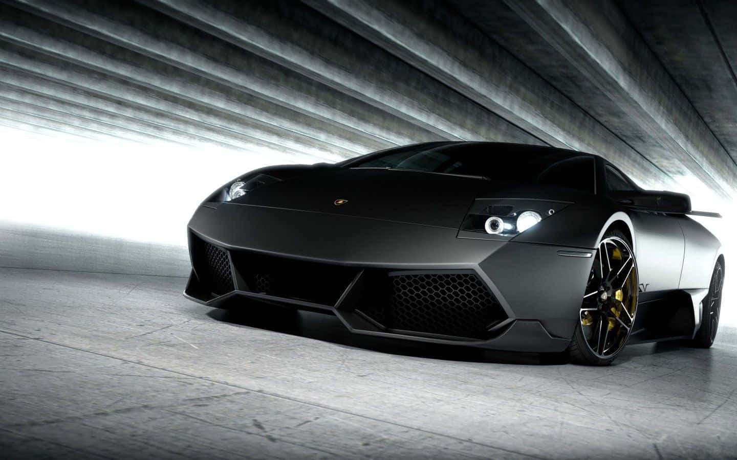 Lamborghini Murciélago 桌布 壁紙 — 一輛啞光黑色藍寶堅尼跑車配金色輪圈，在混凝土隧道天花板下被戲劇性地照亮。