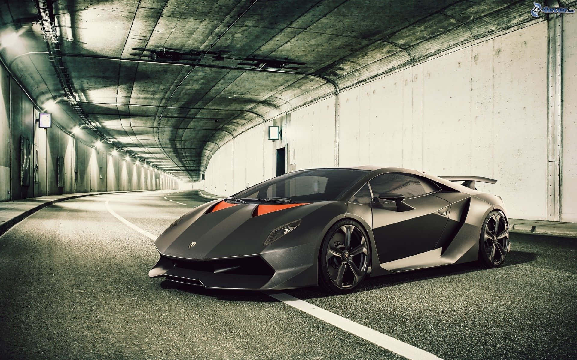 Lamborghini Sesto Elemento 桌布 壁紙 — 一輛時尚的啞光黑色藍寶堅尼跑車帶有橙色點綴，停放在一條長長的混凝土隧道中。
