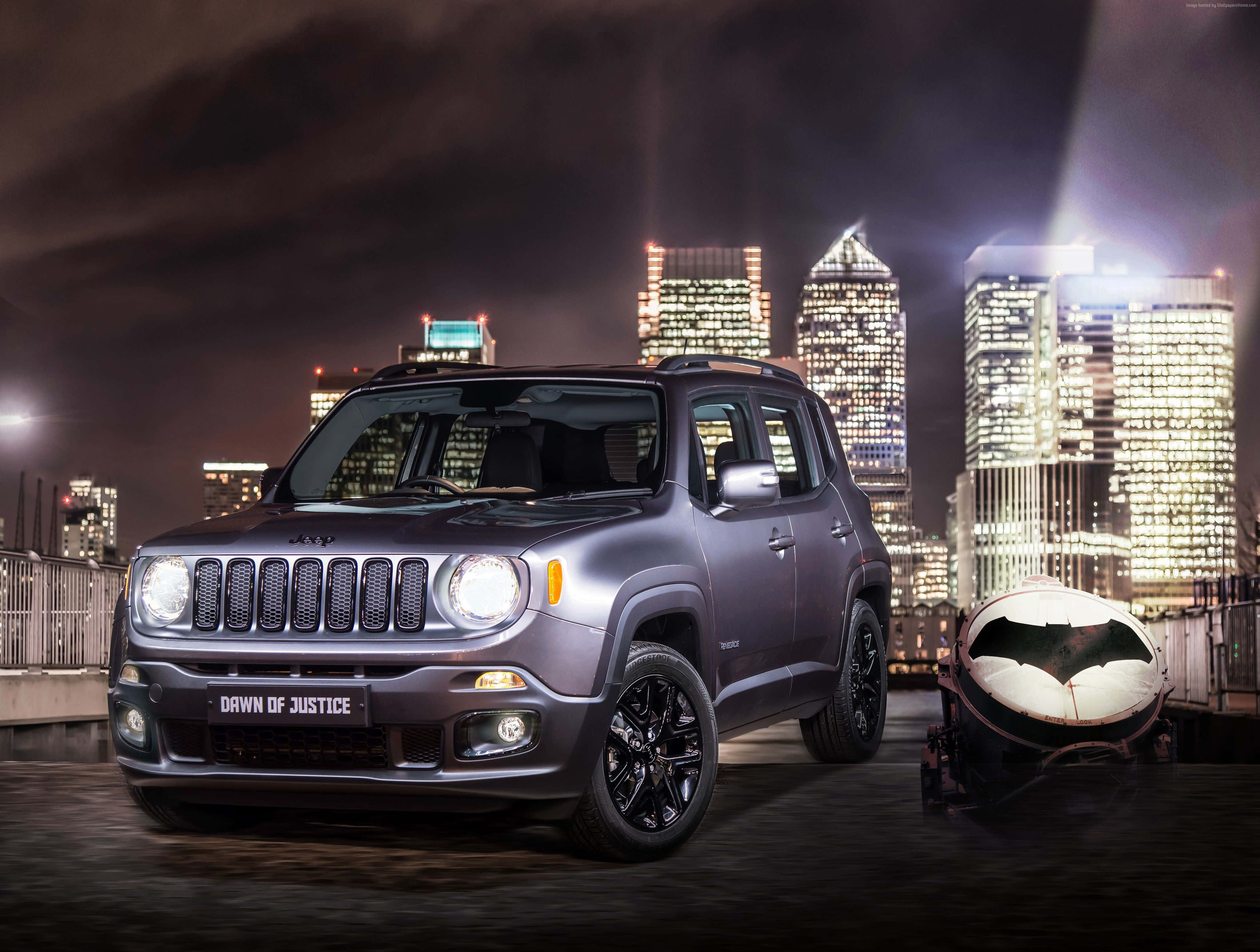 Jeep Renegade 桌布 壁紙 — 一架啞光灰色Jeep Renegade掛著「Dawn of Justice」車牌，夜晚站在屋頂上，旁邊是蝙蝠俠的Batmobile，背景是閃爍的城市天際線。