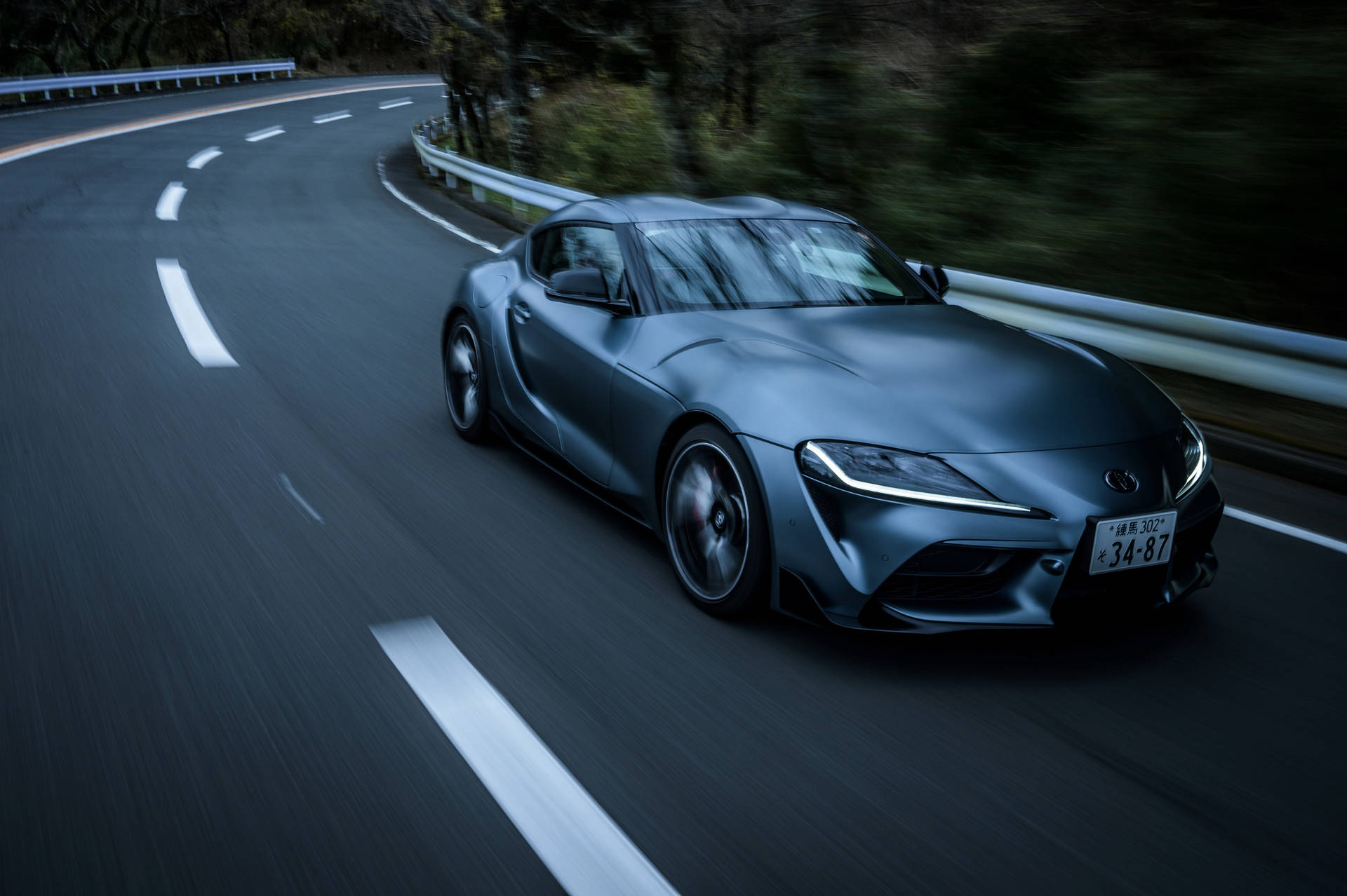 啞光灰色跑車在蜿蜒的道路上黃昏時分疾馳。 — Toyota Supra 壁紙