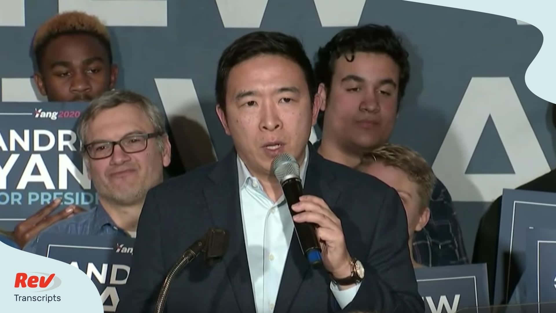 美國 桌布 壁紙 — 楊安澤在競選活動中對著麥克風講話，周圍是舉著標語牌的支持者。