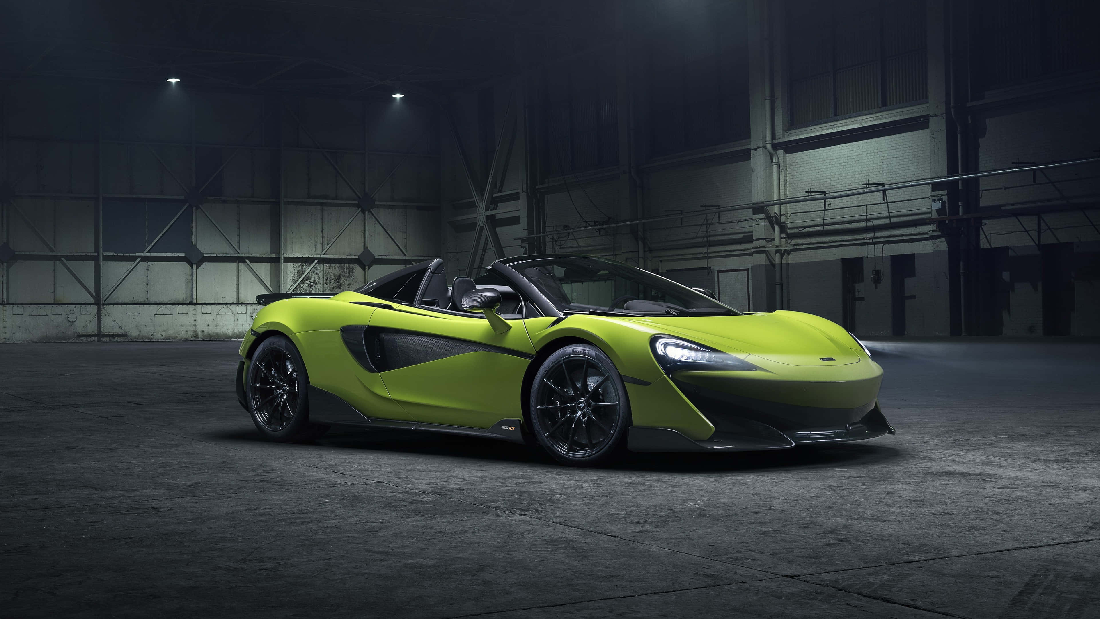 Mclaren 600lt 桌布 壁紙 — 一輛充滿活力的萊姆綠色McLaren跑車在昏暗的工業倉庫中，在聚光燈下閃閃發光。
