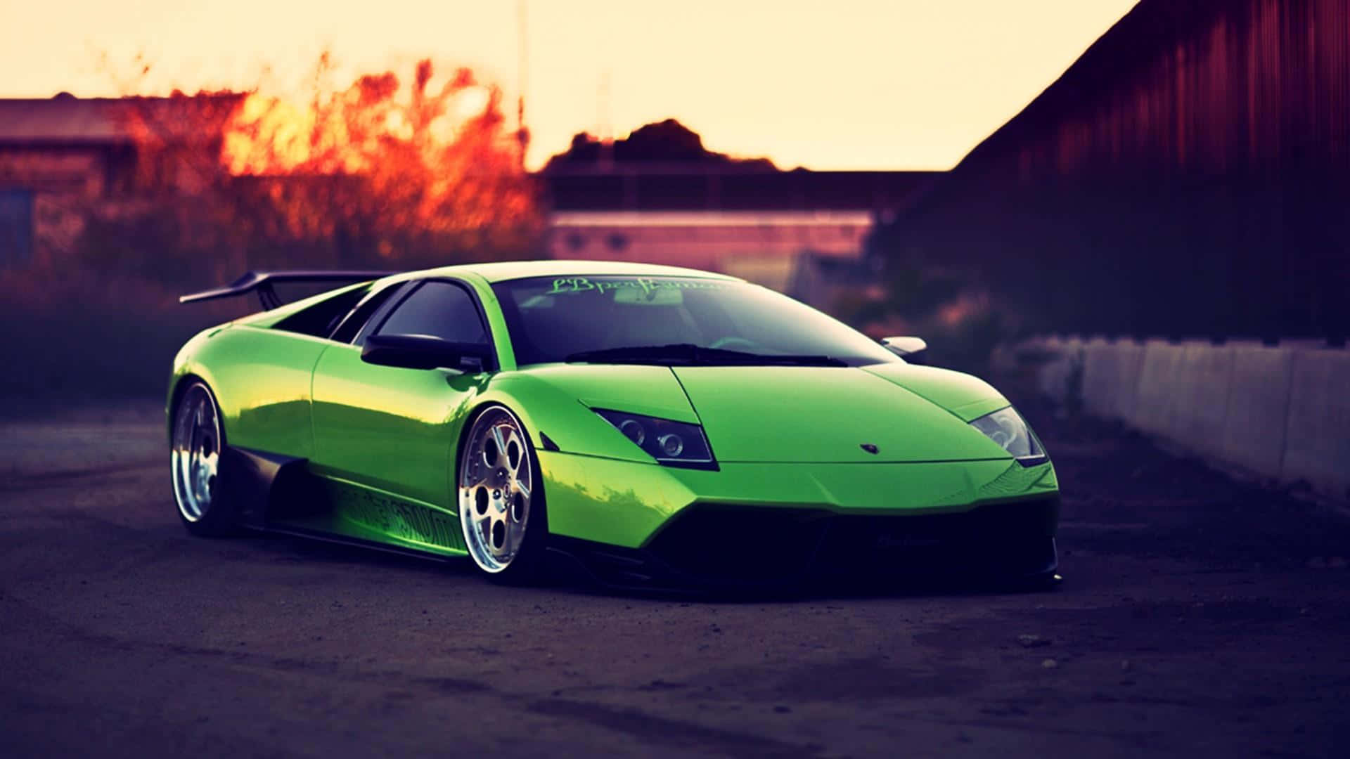 Lamborghini Murciélago 桌布 壁紙 — 一輛充滿活力的綠色藍寶堅尼 Murciélago 在熾熱的夕陽下閃閃發光，在粗糙的城市街道上投下長長的影子。