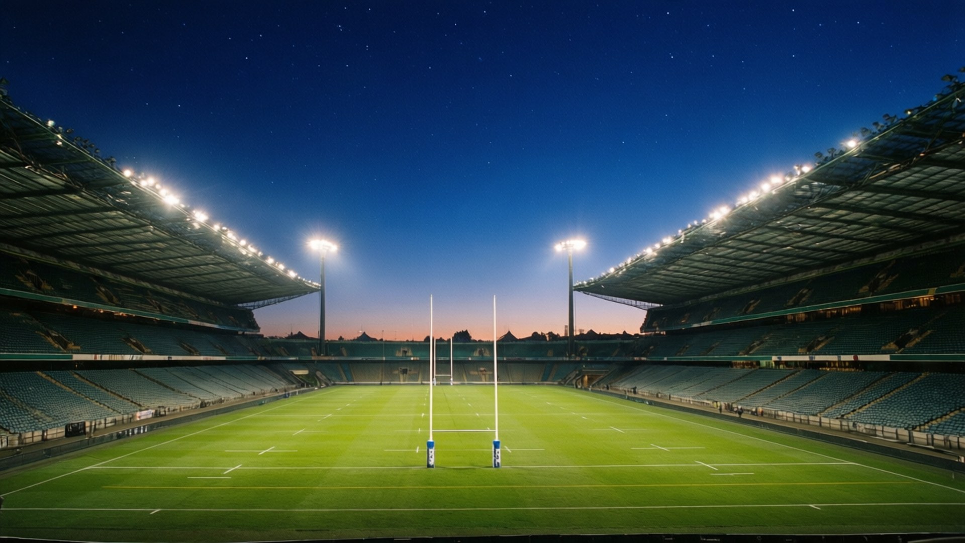 Empty Stadium Twilight 壁紙 — 一個廣闊空無一人的橄欖球場，在繁星點點的暮色天空下，發光的泛光燈照亮綠色球場。