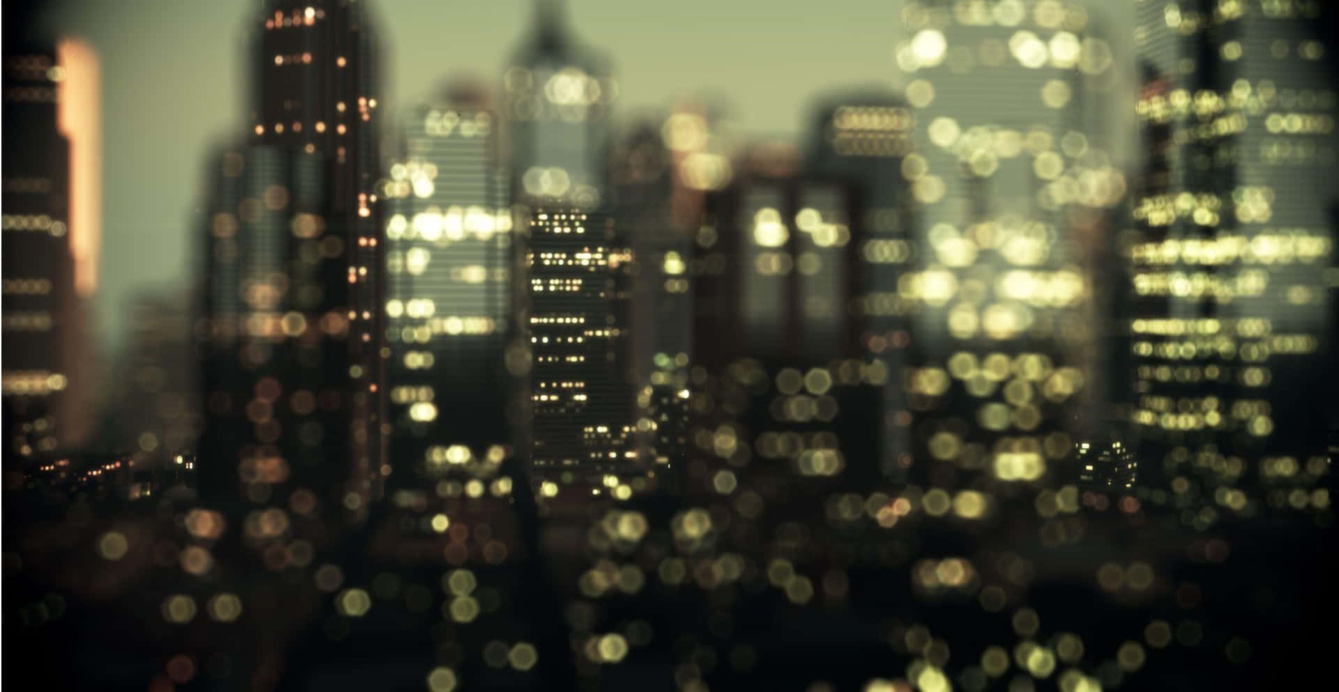  壁紙 — 夜晚模糊的城市景觀，摩天大樓散發著閃爍的散景燈光，營造出夢幻般的城市光芒。