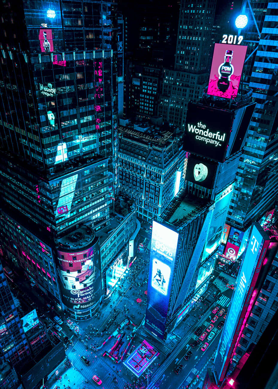  壁紙 — 夜晚霓虹燈照亮城市峽谷的鳥瞰圖，高聳的摩天大樓散發出電光藍和粉紅色的光芒。