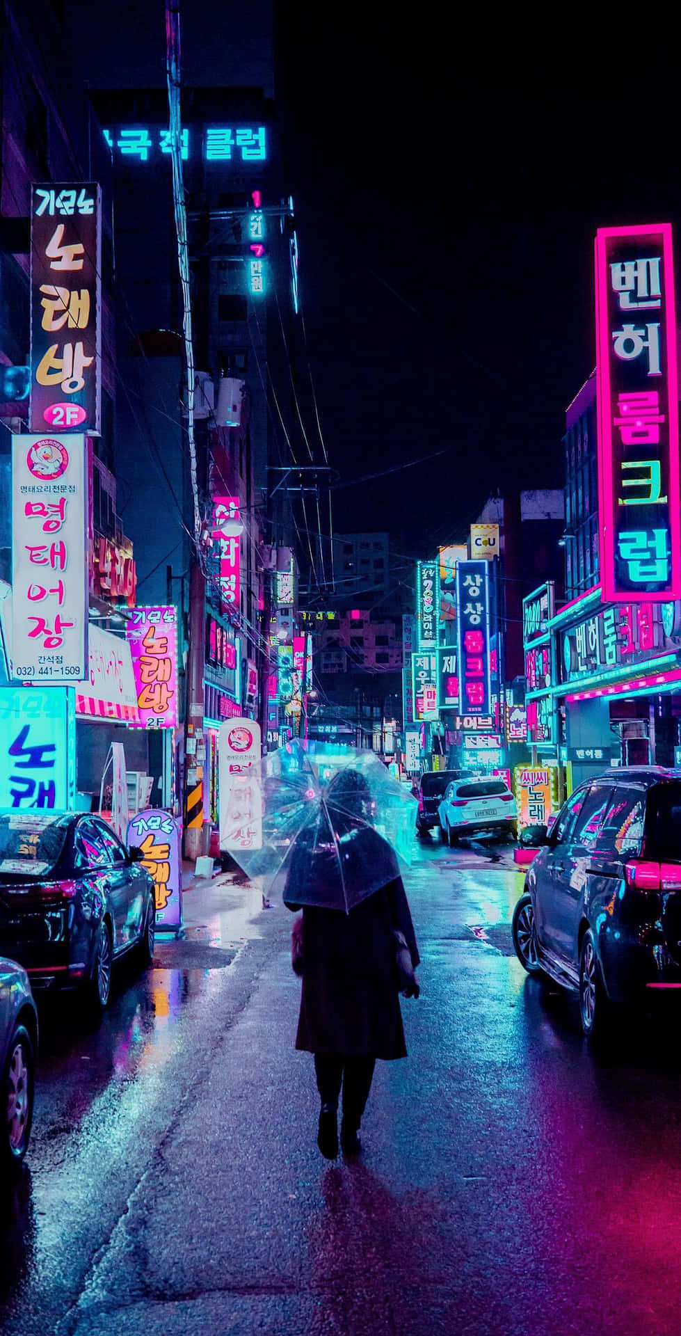  壁紙 — 夜晚，一個孤獨的身影走在被雨水浸濕的霓虹燈街道上，發光的招牌在潮濕的路面上反射。