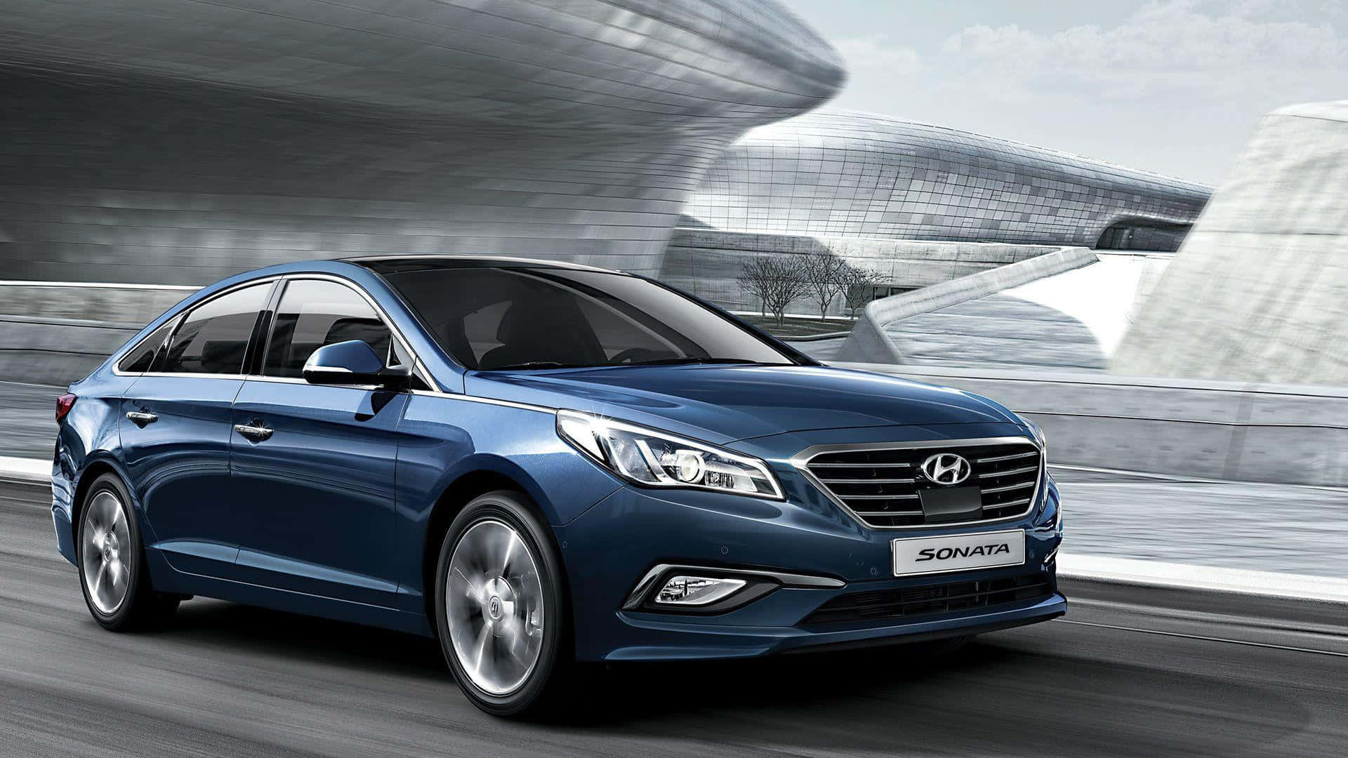 Hyundai Sonata 桌布 壁紙 — 一輛流線型的藍色現代索納塔在明亮的天空下，沿著現代高速公路飛馳，經過未來主義的玻璃建築。