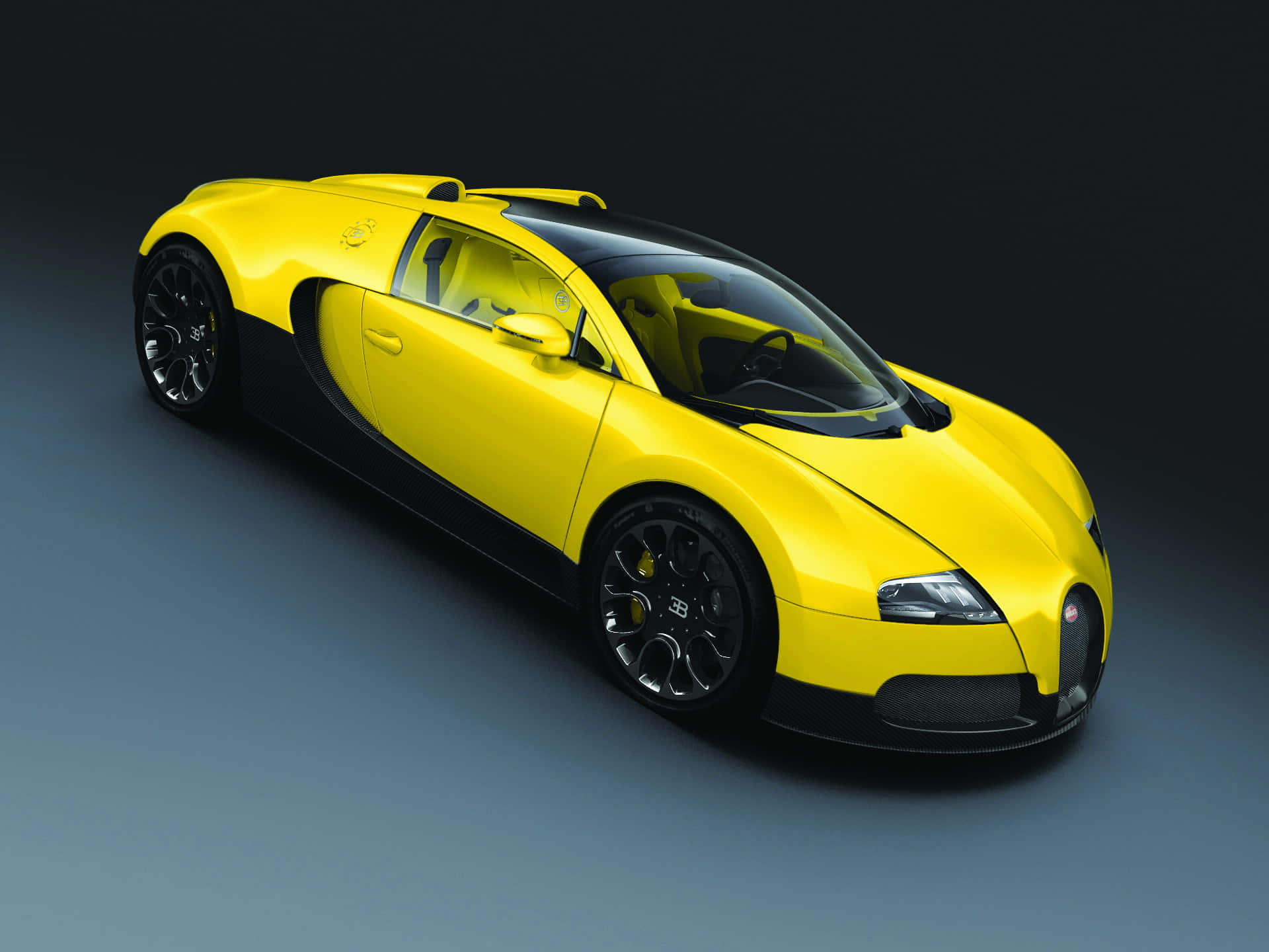 Bugatti Veyron 桌布 壁紙 — 一輛充滿活力的黃色Bugatti Veyron超級跑車，帶有黑色飾邊和光澤表面，在攝影棚環境中拍攝。