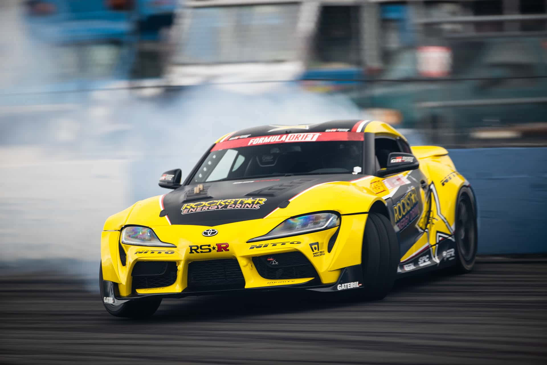 黃色甩尾車在賽道上進行高速甩尾，輪胎冒出煙霧。 — Toyota Supra 壁紙