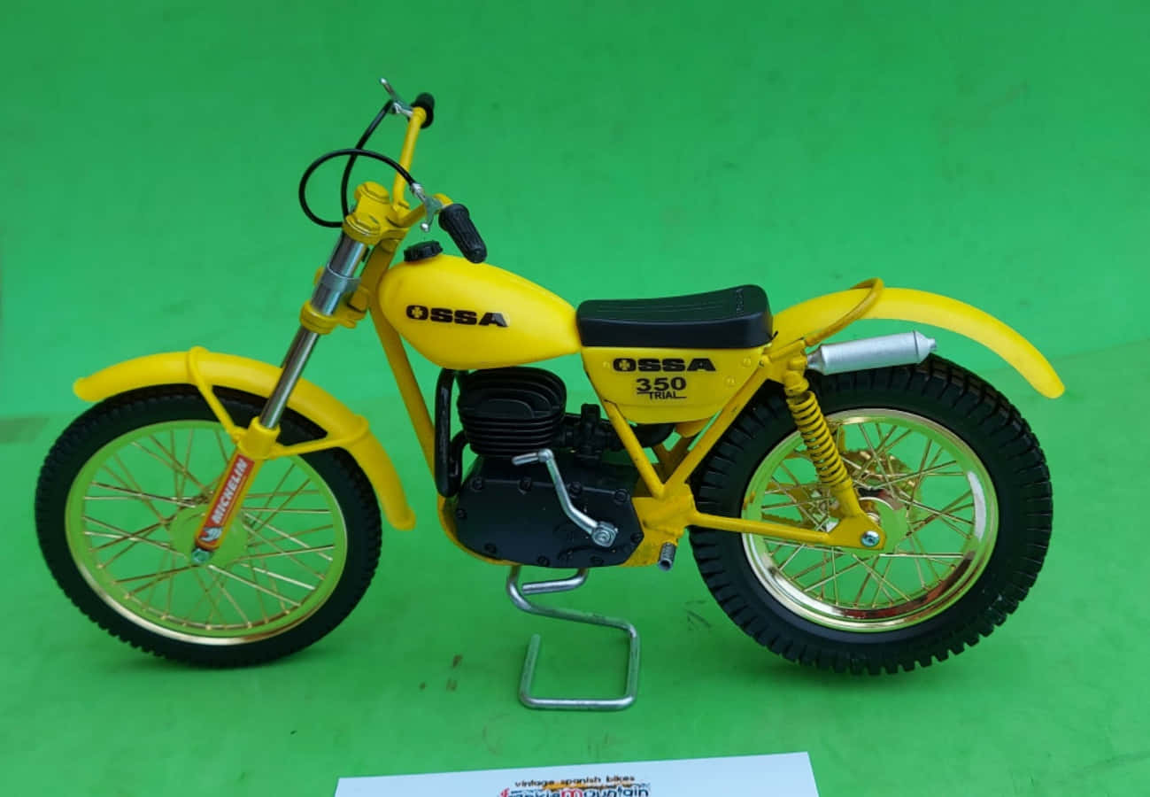 Ossa Motorcycle 桌布 壁紙 — 一輛亮黃色的Ossa 350 Trial機車模型，在綠色背景上帶有精細的鍍鉻和黑色裝飾。