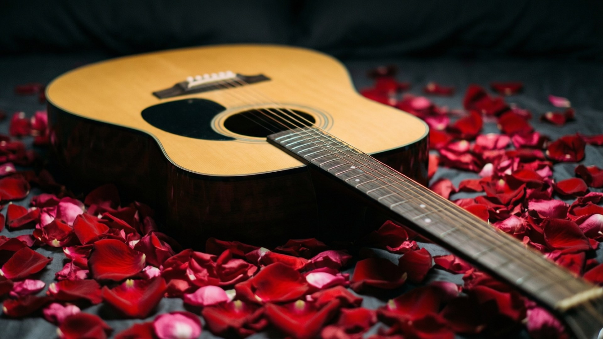 Rose Petal Serenade 壁紙 — 一把木吉他放在深色布料表面上，周圍散落著紅色玫瑰花瓣。