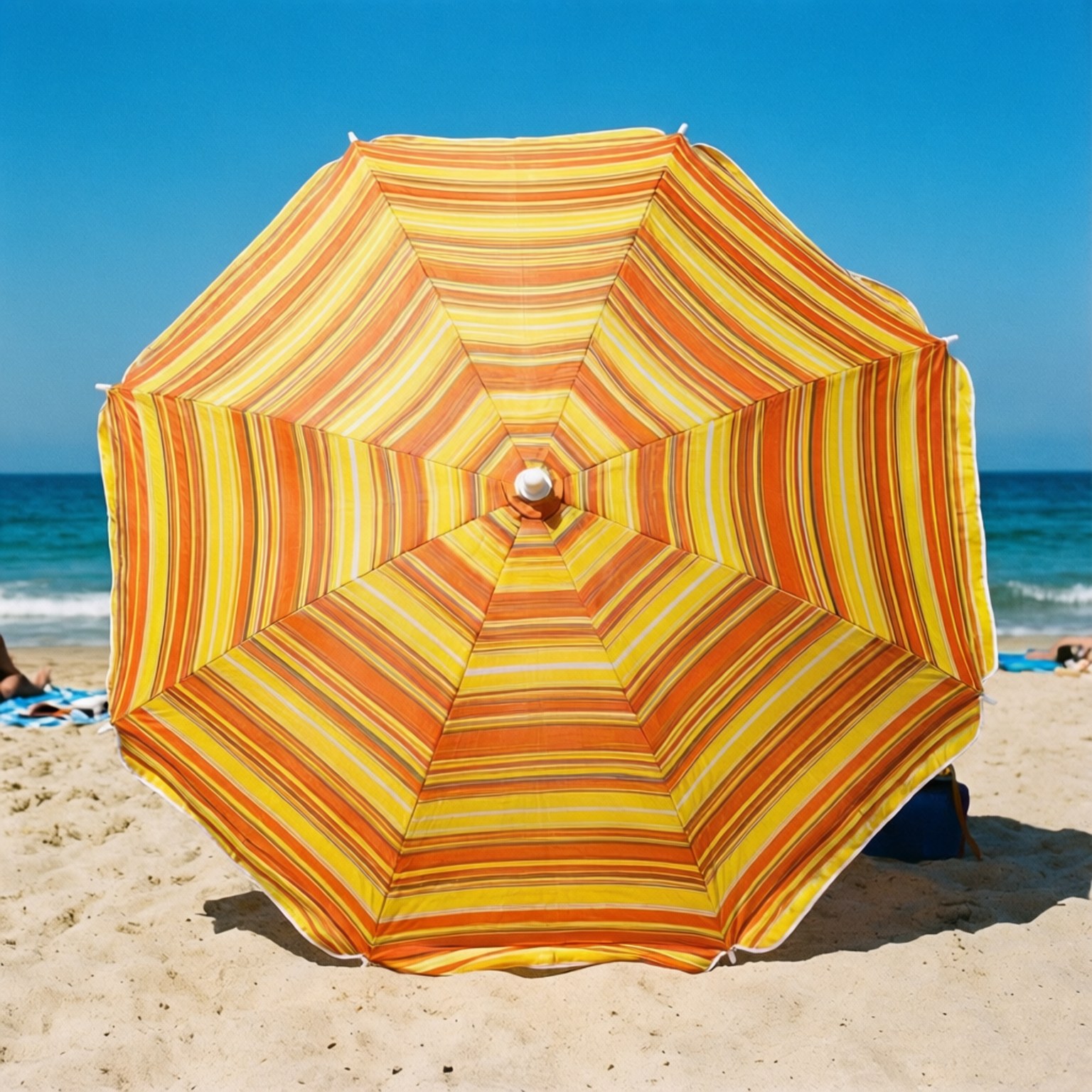 Beach Umbrella Stripes 壁紙 — 一把鮮豔的橙色和黃色條紋沙灘傘在沙灘上張開，背景是海洋和清澈的藍天。