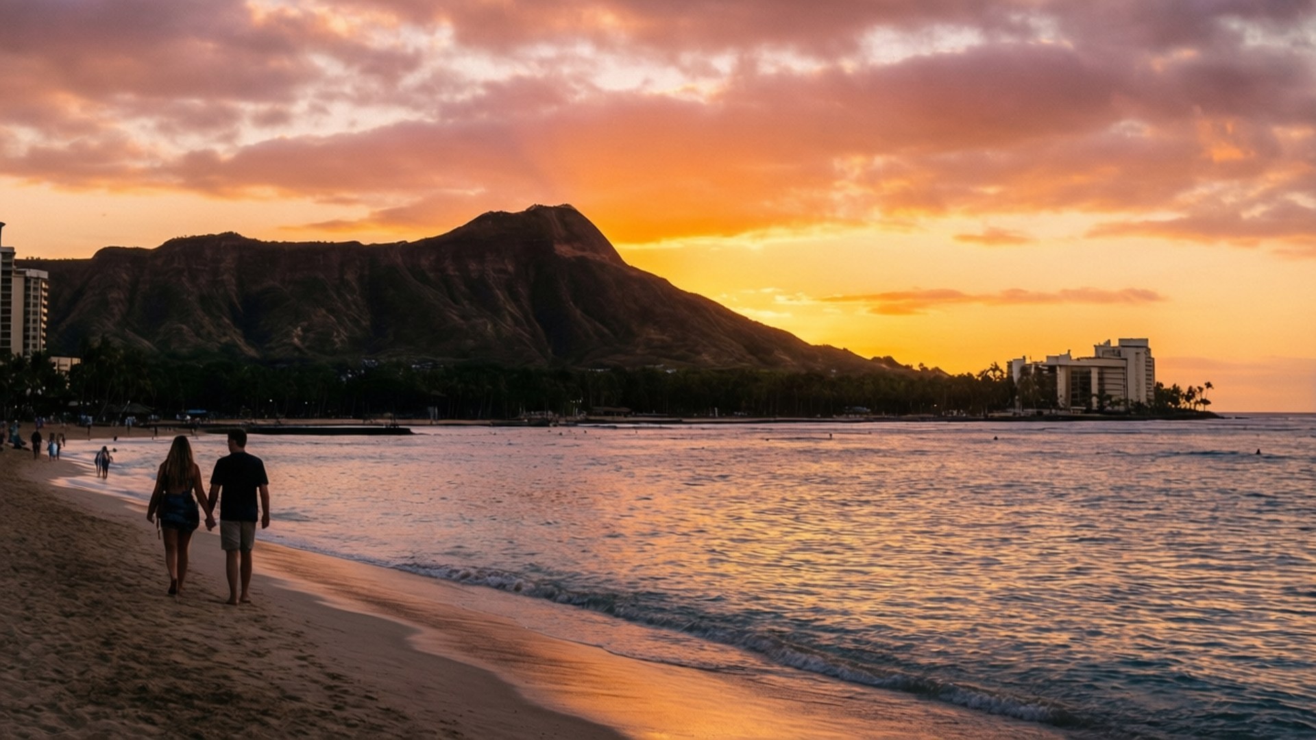 Waikiki Diamond Head Sunset 壁紙 — 一對情侶手牽手沿著沙灘漫步，夕陽西下，鑽石頭山在火紅橙粉色的天空映襯下呈現剪影。