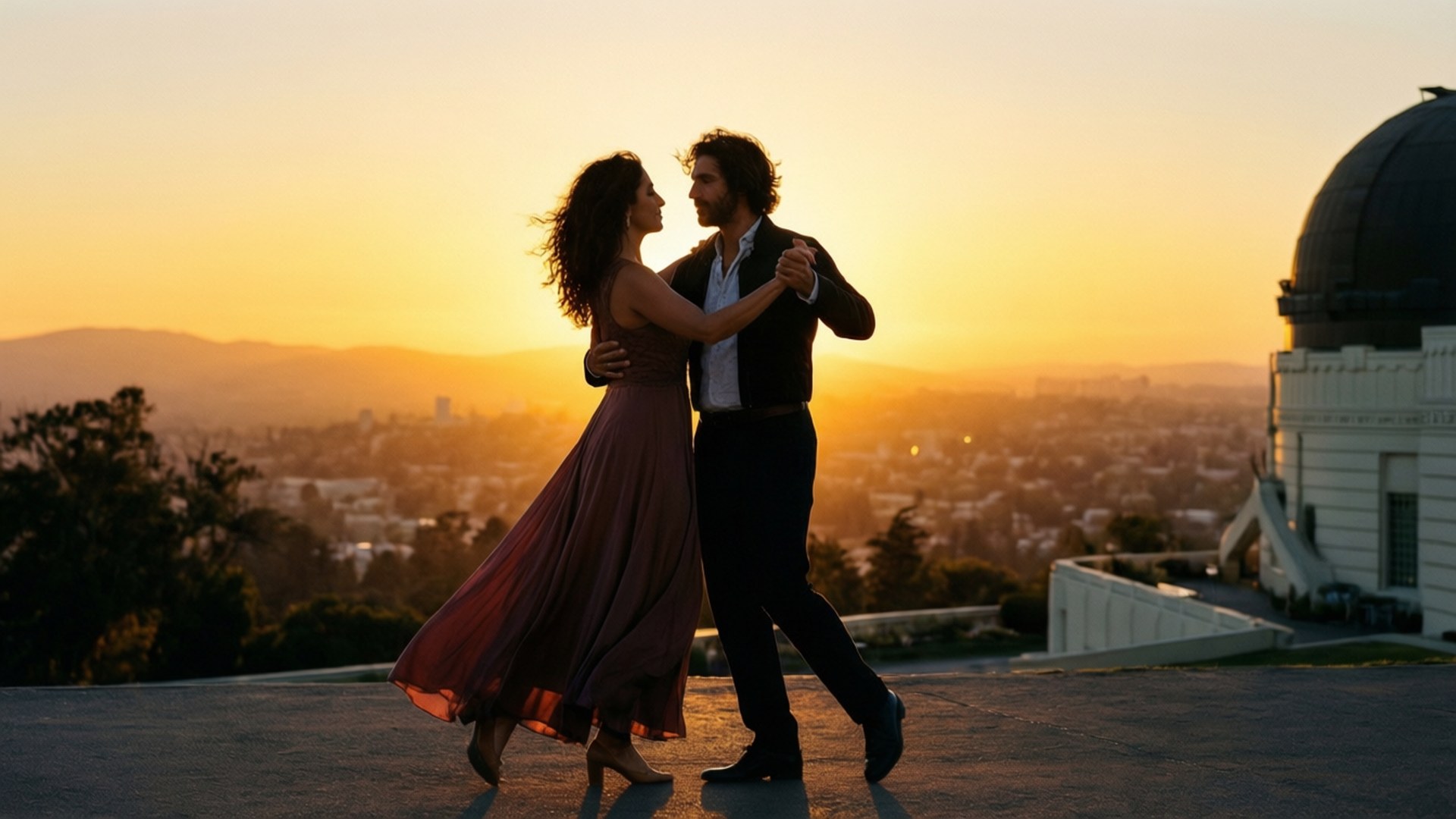 la la land 桌布 壁紙 — 一對情侶在格里菲斯天文台頂部以剪影跳舞，金色夕陽光芒沐浴著下方的城市景觀。