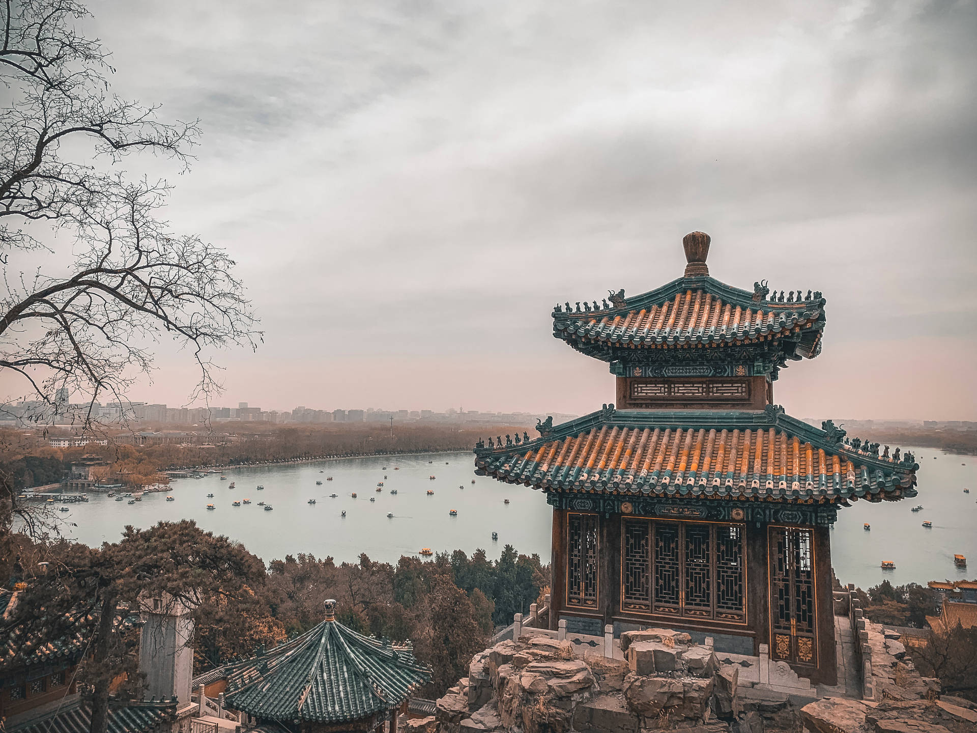 古老的中式亭閣矗立在岩石上，俯瞰著湖面上的船隻。 — 中文 壁紙