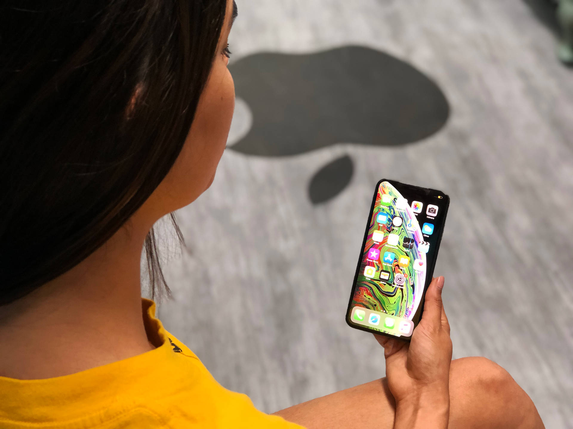 室內手持顯示彩色抽象桌布的智慧型手機的人。 — iPhone 13 Pro Max 壁紙