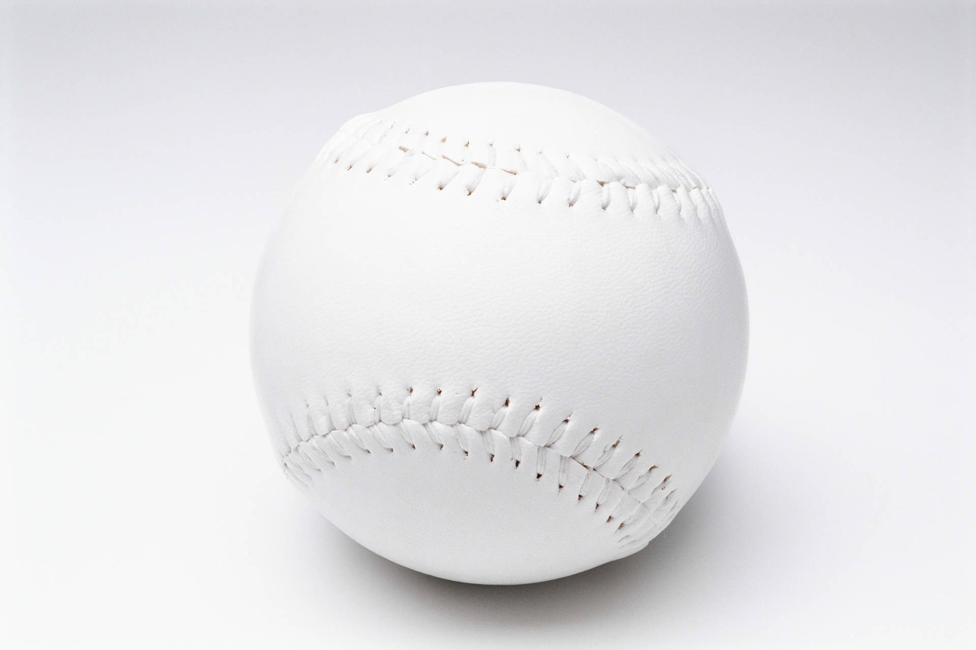在純白背景上，一個可見縫線的白色棒球。 — MLB 壁紙