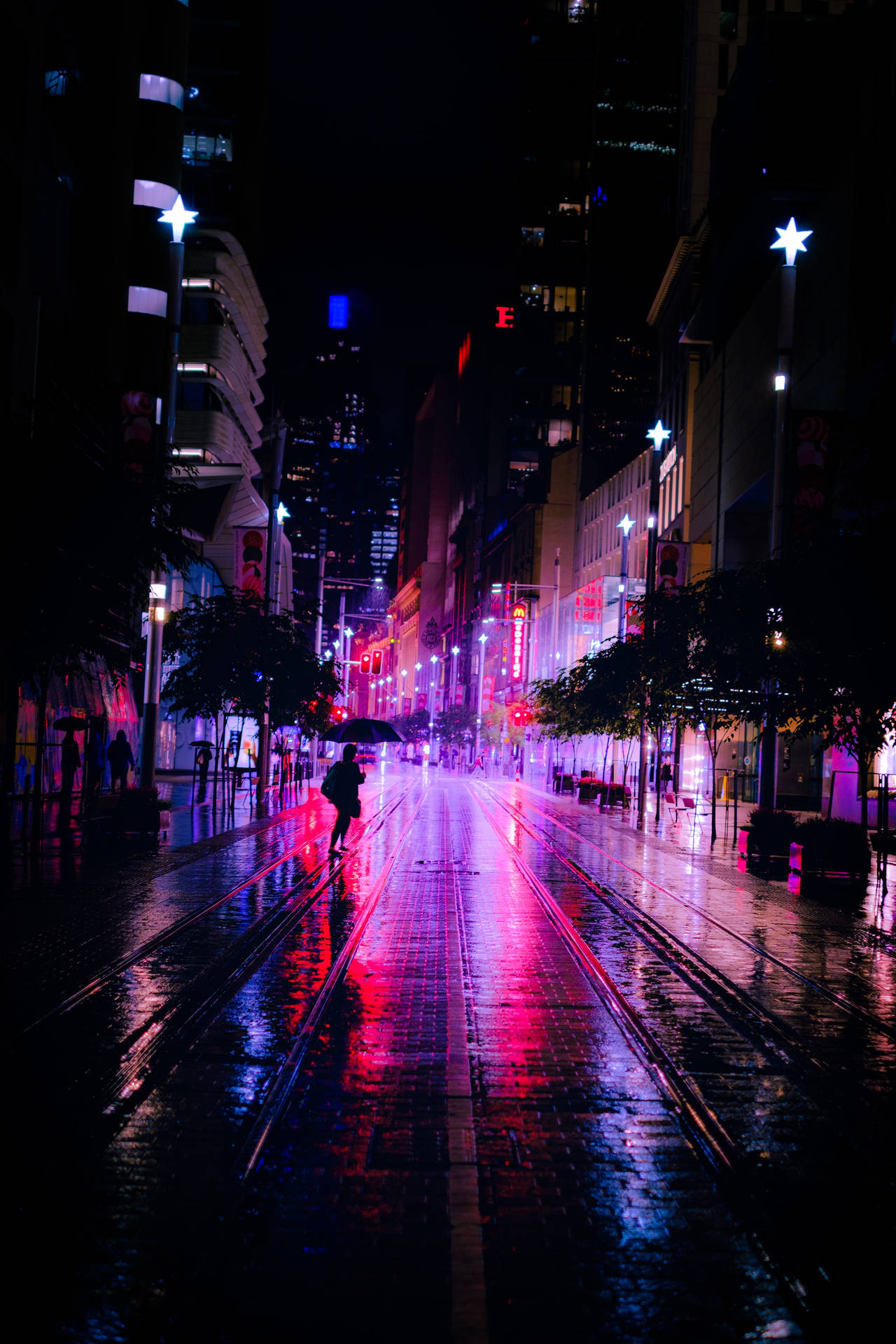 夜晚在霓虹燈下，一個人在濕漉漉的城市街道上獨自行走。 — 夜景城市 壁紙