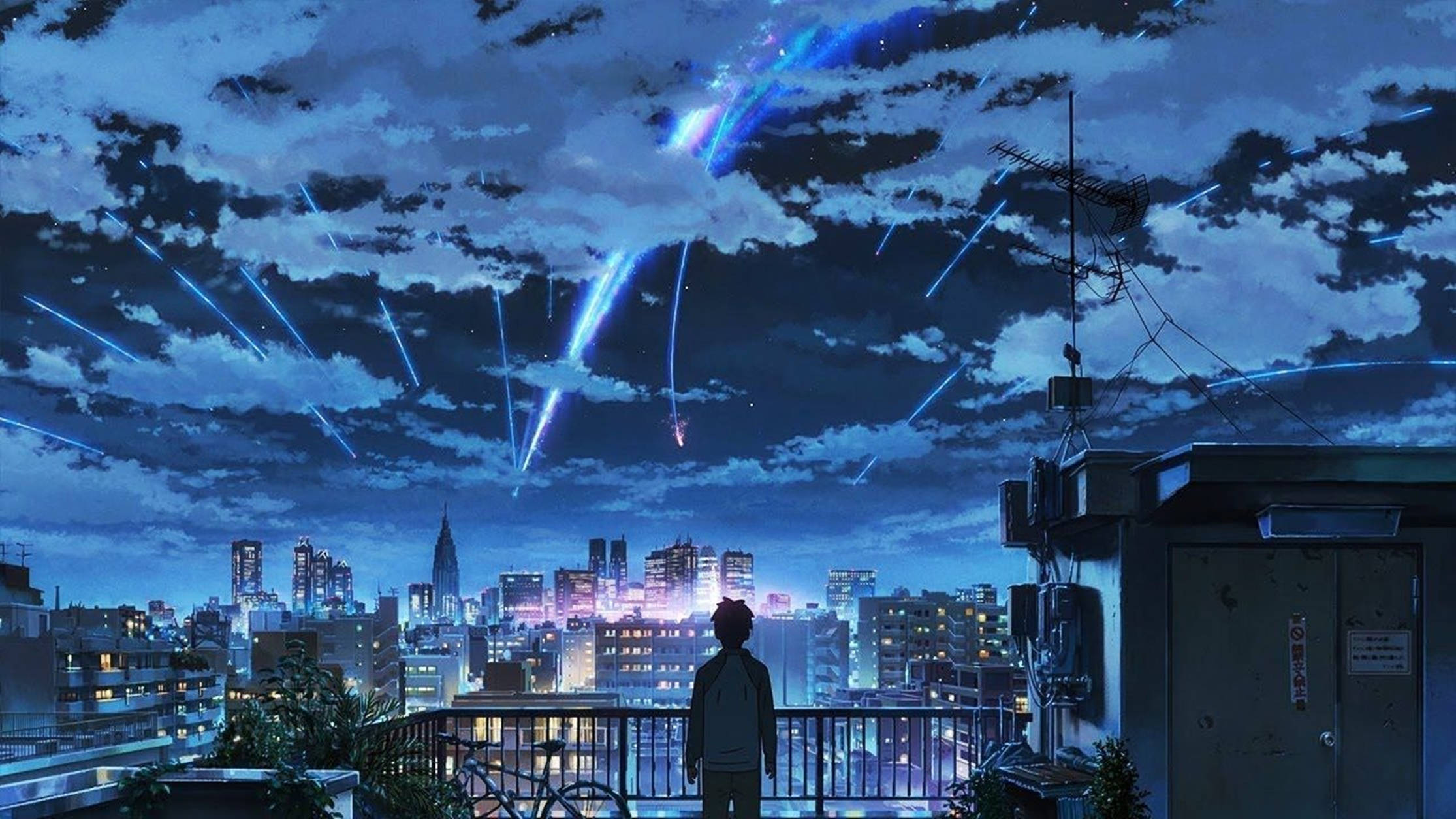 屋頂上的人看著藍色燈光在夜間落在城市上 — 動漫男孩 壁紙