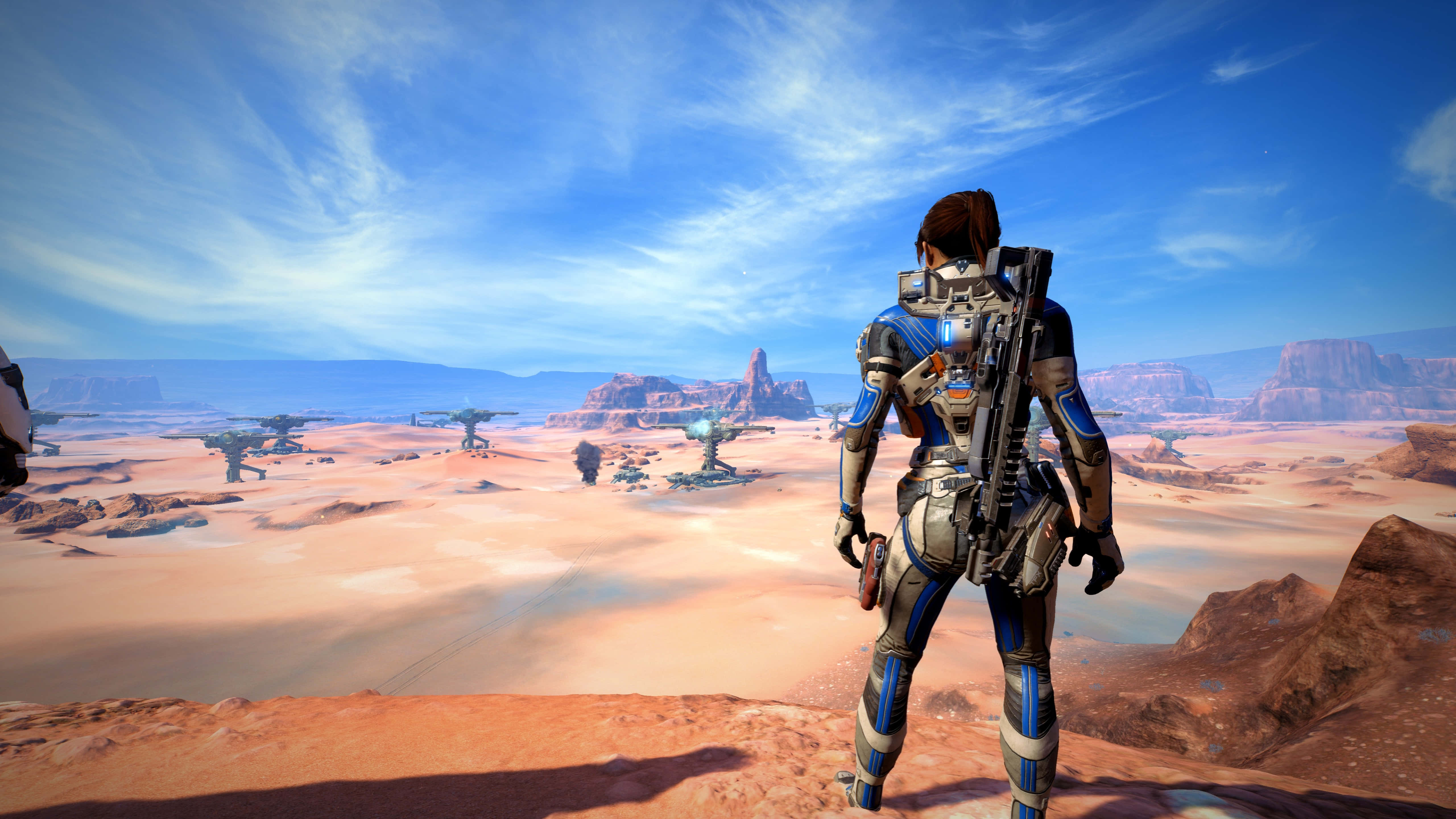 Mass Effect Andromeda 桌布 壁紙 — 一個孤獨的裝甲太空人站在紅色沙漠懸崖上，俯瞰著廣闊的外星荒地，天空湛藍。
