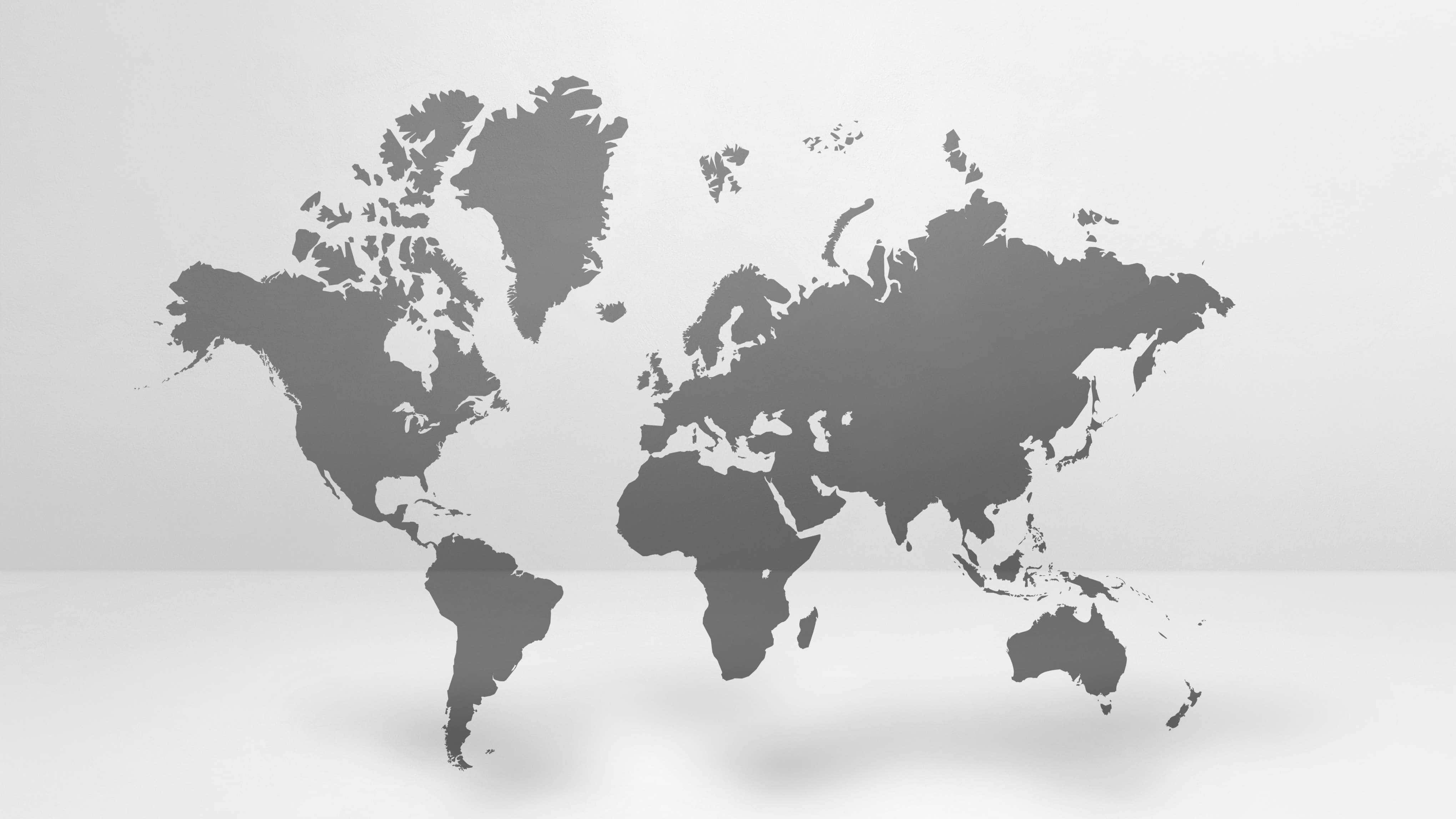 World Map Desktop 桌布 壁紙 — 一個極簡灰色世界地圖剪影漂浮在白色表面上，投射出柔和陰影。