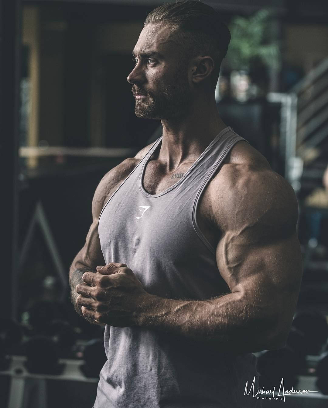運動型男人，肌肉線條分明，在健身房穿著灰色背心站立 — Chris Bumstead 壁紙