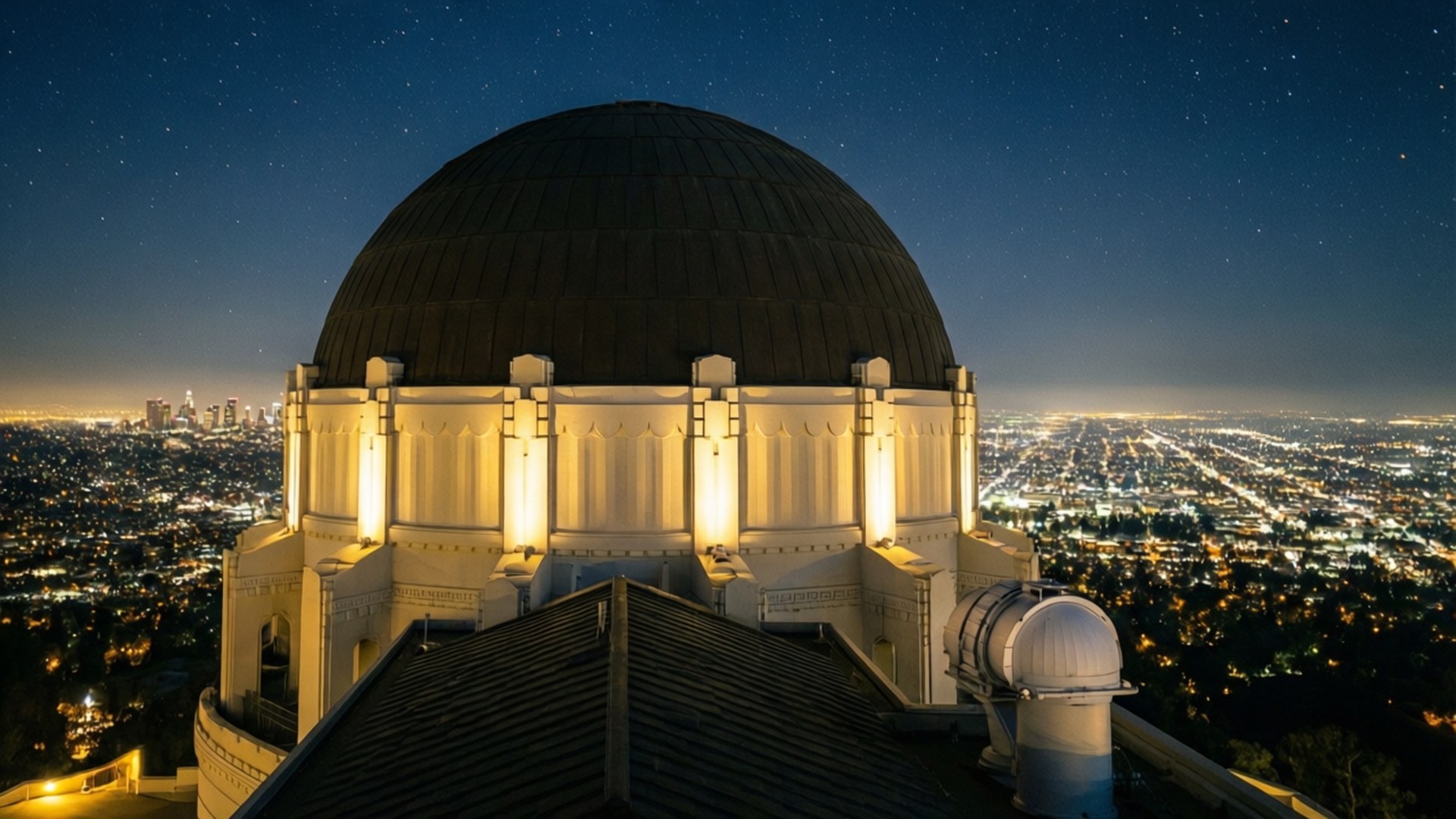 Griffith Observatory Night Lights 壁紙 — 一個巨大的圓頂天文台在繁星點點的夜空下溫暖地發光，俯瞰著閃爍燈光蔓延的城市景觀。