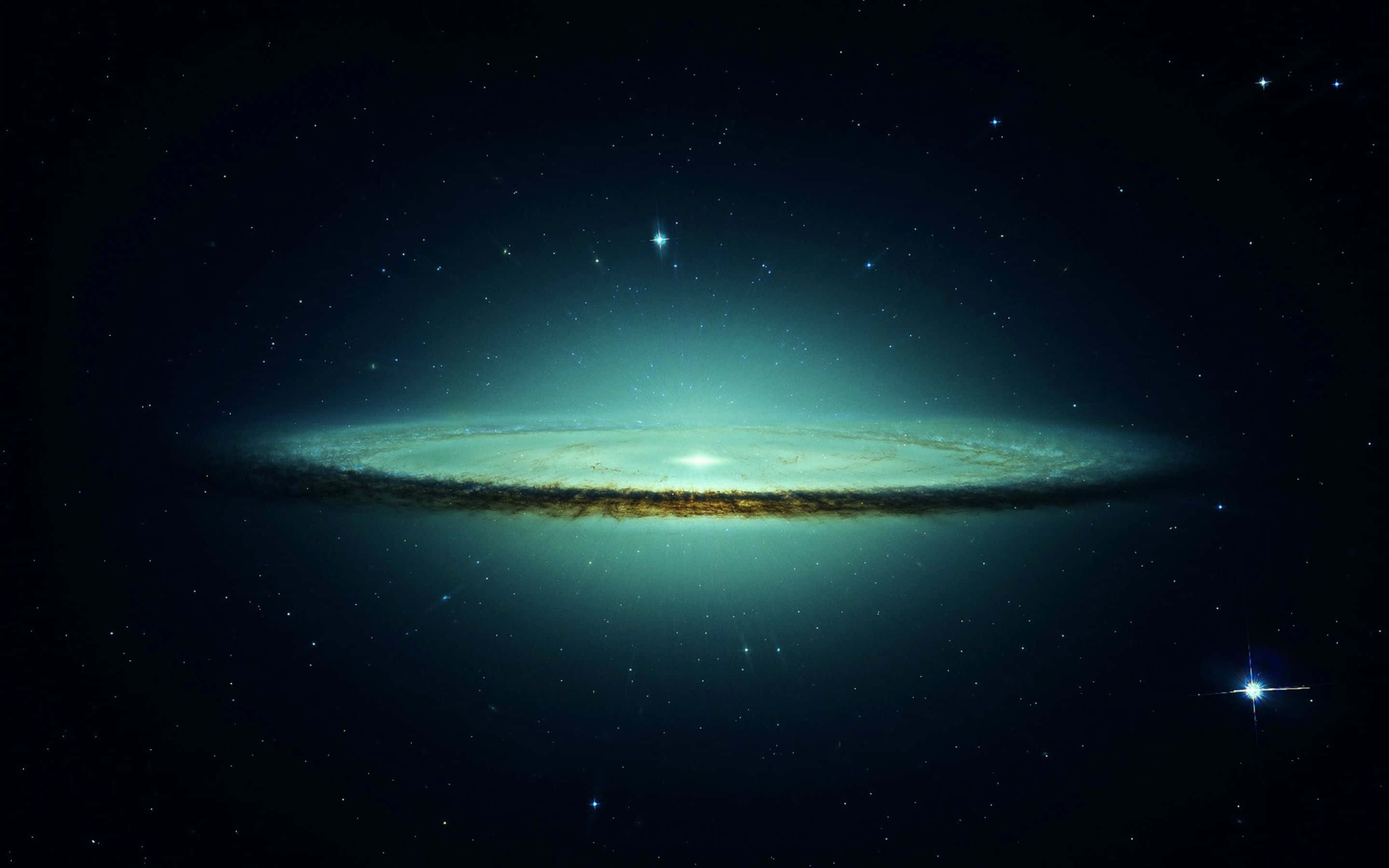 一個發光的螺旋星系，帶有青綠色的旋臂和金色的塵埃，背景是繁星點點的夜空。 — Macbook Pro 壁紙