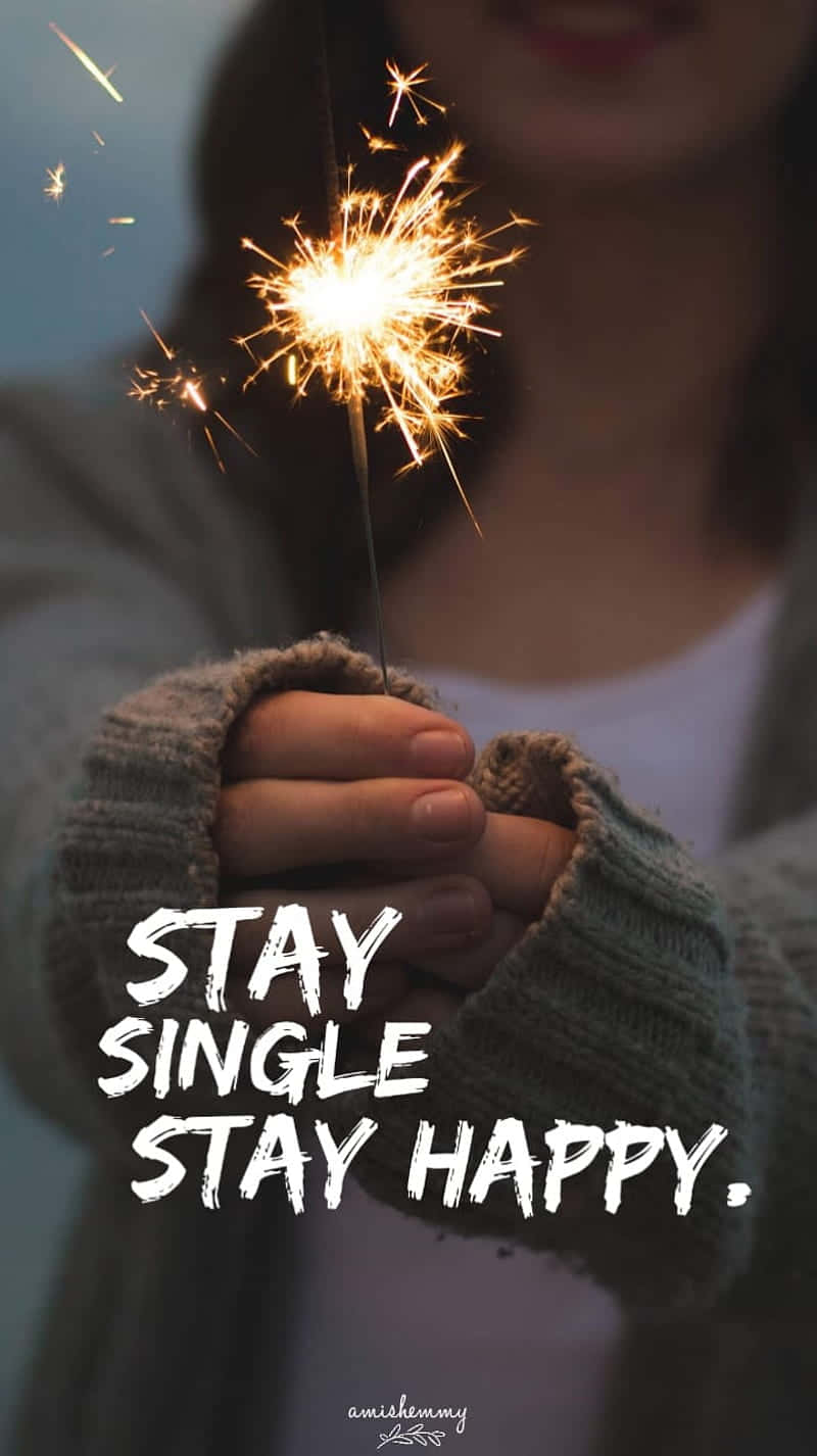  壁紙 — 一個人手持明亮閃爍的煙火，背景柔和模糊，並有粗體文字 stay single stay happy。