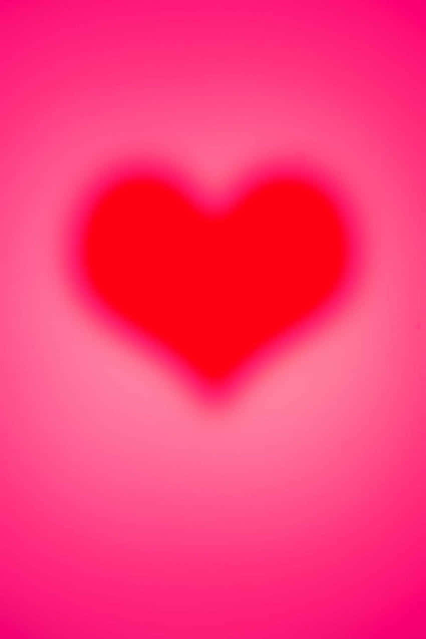 Pink Heart Aura 桌布 壁紙 — 一個柔和模糊的紅色心形，置中於漸變粉紅色背景上，邊緣發光。
