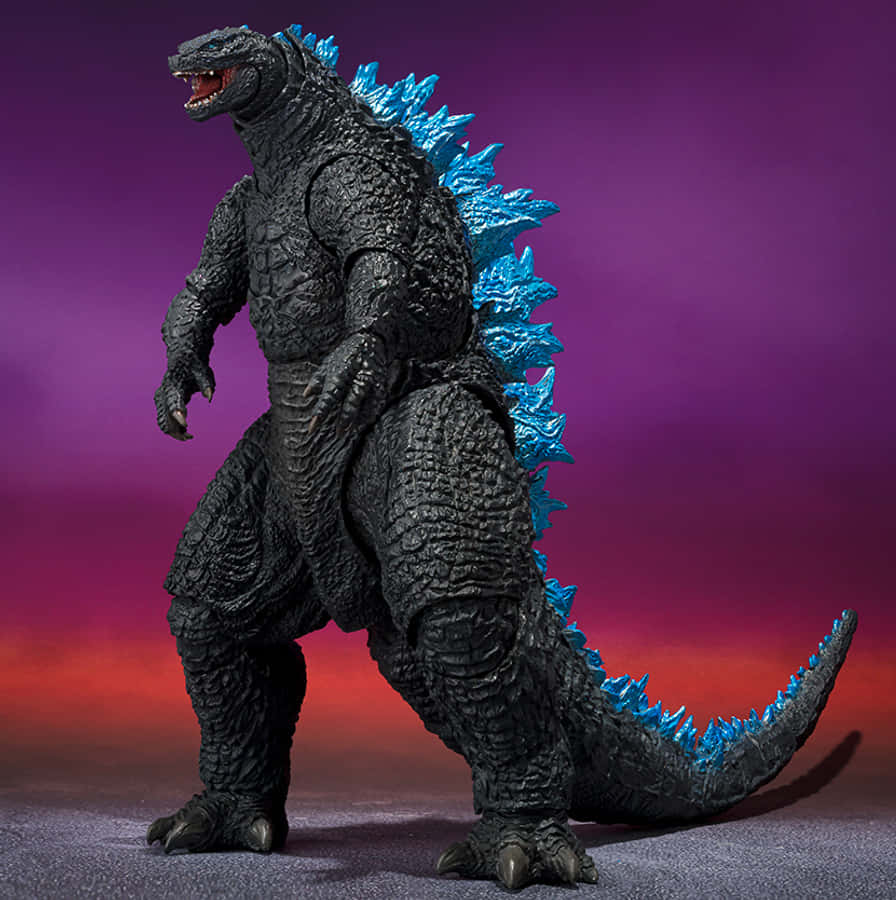 Godzilla X Kong The New Empire 桌布 壁紙 — 一個細節豐富的黑色哥吉拉可動人偶，帶有發光的藍色背鰭，站在紫色和紅色的漸變背景前。