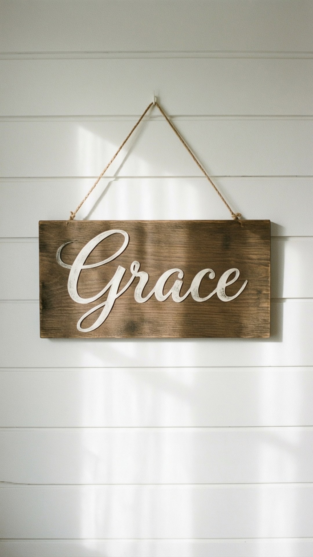 Wooden Sign 桌布 壁紙 — 一個質樸的木牌，上面用白色草書寫著「Grace」，用麻繩掛在沐浴在柔和陽光下的白色拼接牆上。