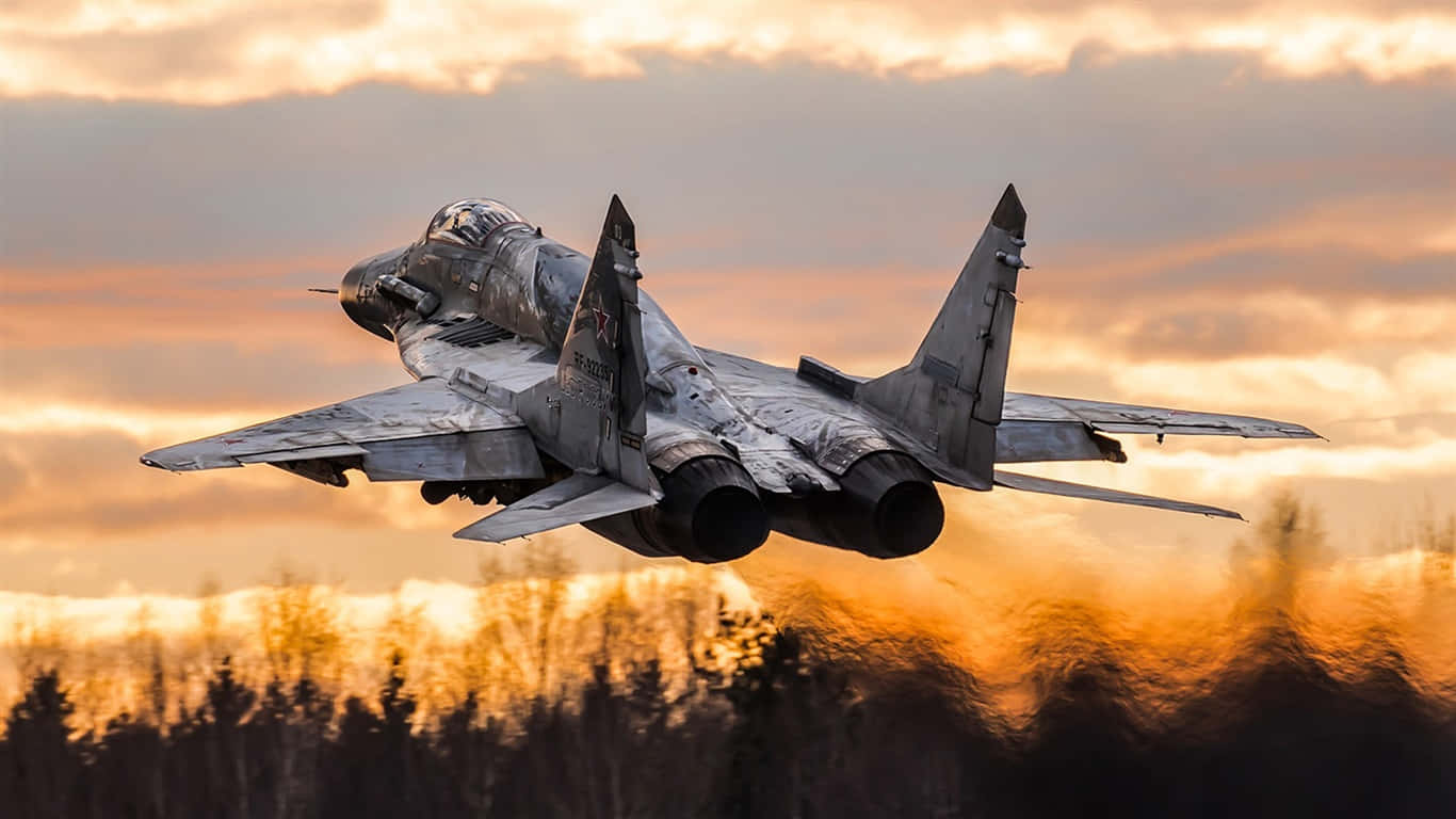 一架軍用噴射機在日落時低空飛過森林。 — 1366X768 壁紙