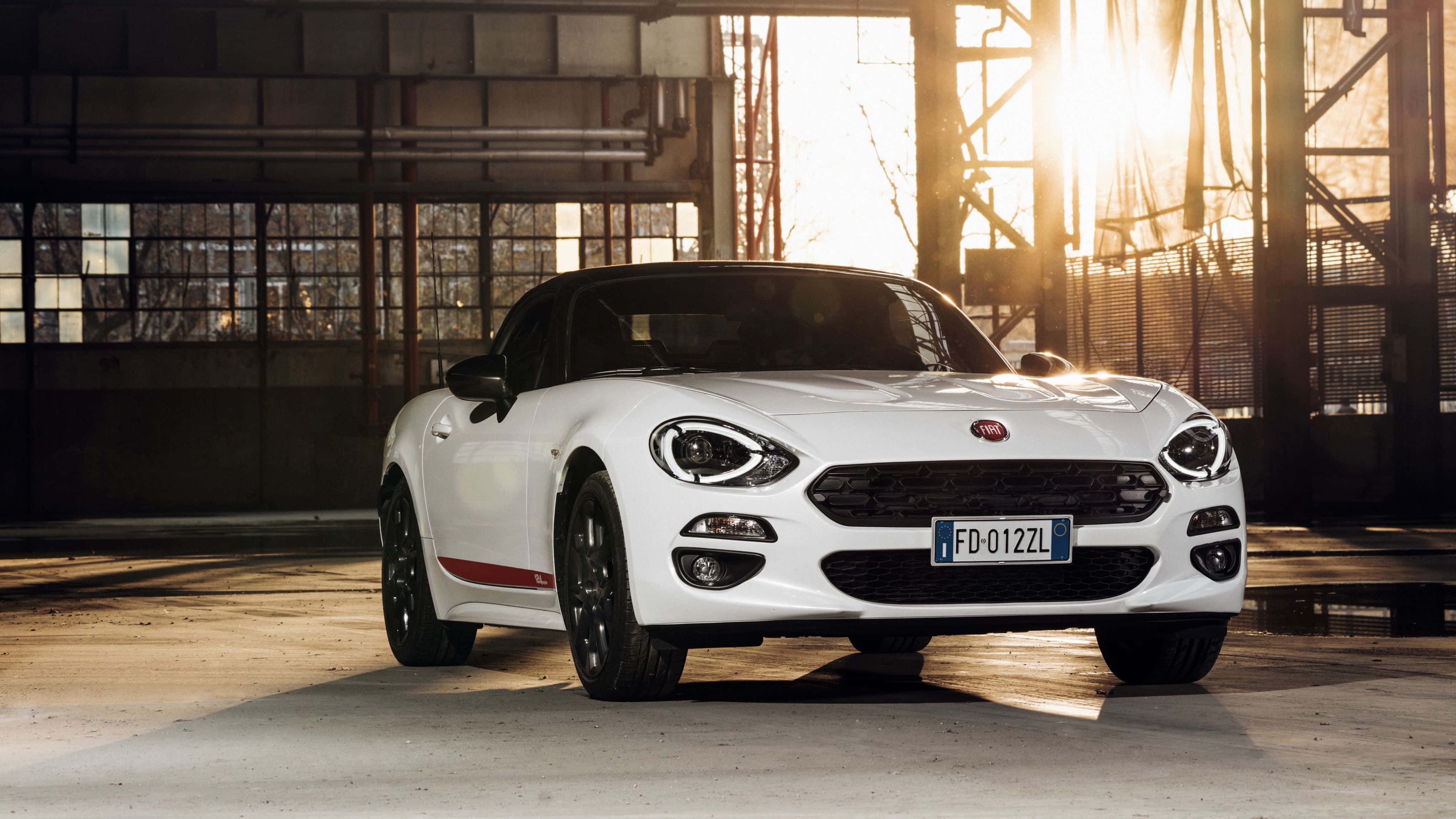 Fiat 500l 桌布 壁紙 — 一架時尚的白色Fiat 124 Spider敞篷車停在工業倉庫內，金色陽光透過窗戶灑進來。