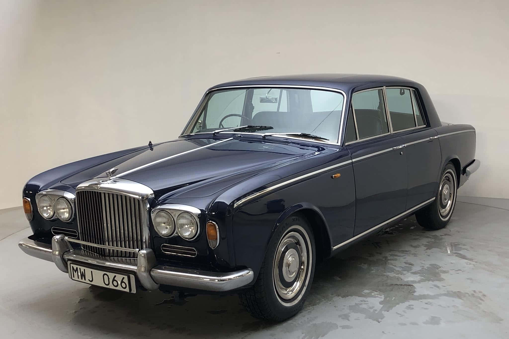Bentley T1 桌布 壁紙 — 一架時尚的海軍藍色復古賓利轎車在簡約白色房間的攝影棚燈光下閃耀。