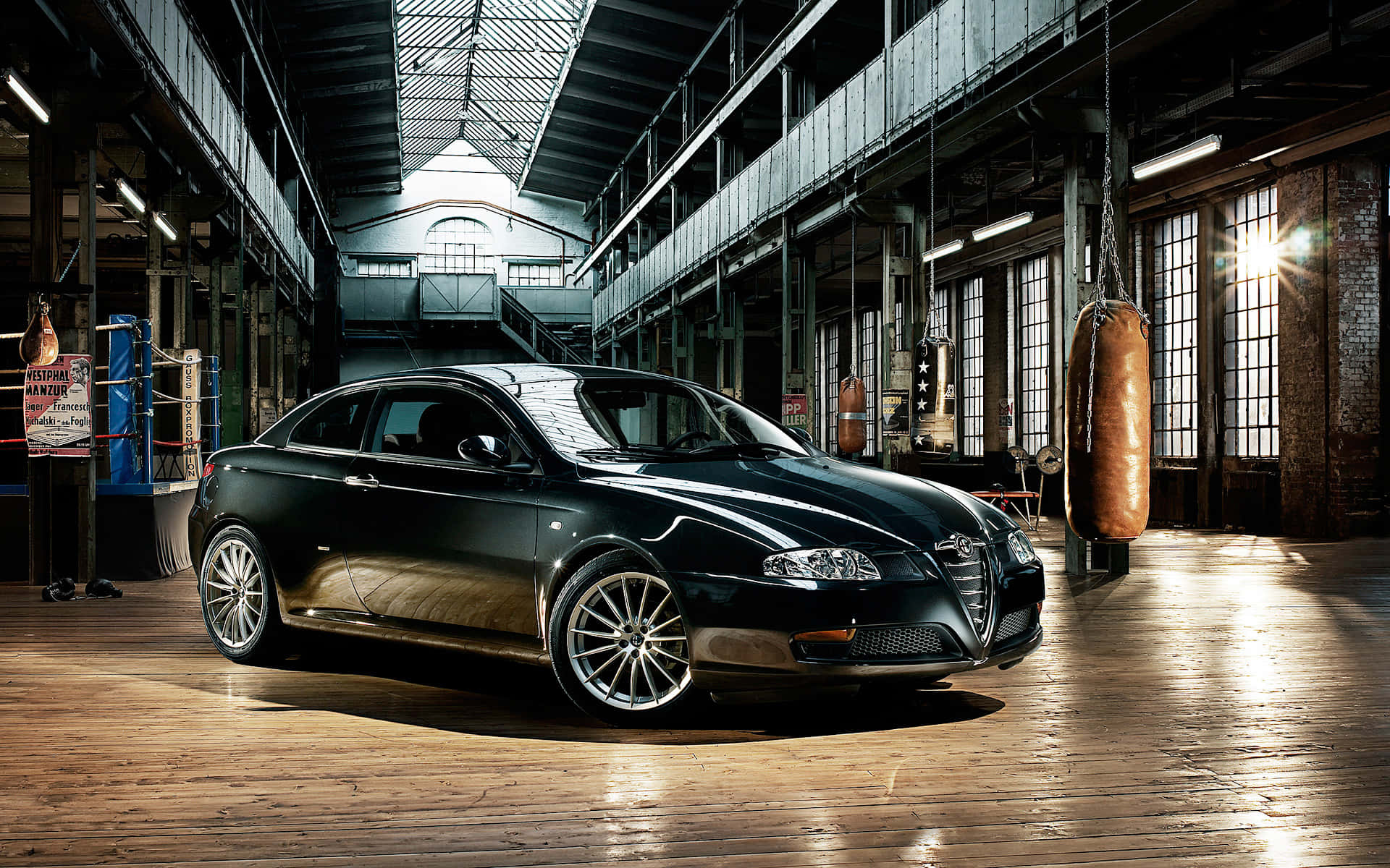 Alfa Romeo Gt 桌布 壁紙 — 一架時尚的黑色愛快羅密歐跑車在寬敞的拳擊館內，在工業照明下閃閃發光，館內有木地板和懸掛的沙包。
