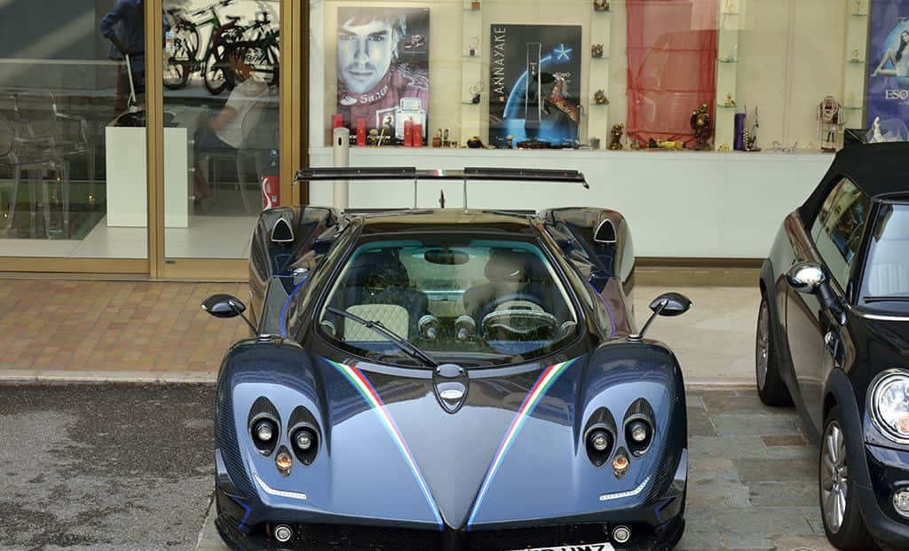 Pagani Zonda Tricolore 桌布 壁紙 — 一架時尚的藍色Pagani超級跑車帶有彩虹條紋，停在濕漉漉的路面上，旁邊是一輛Mini Cooper，前面是商店櫥窗。