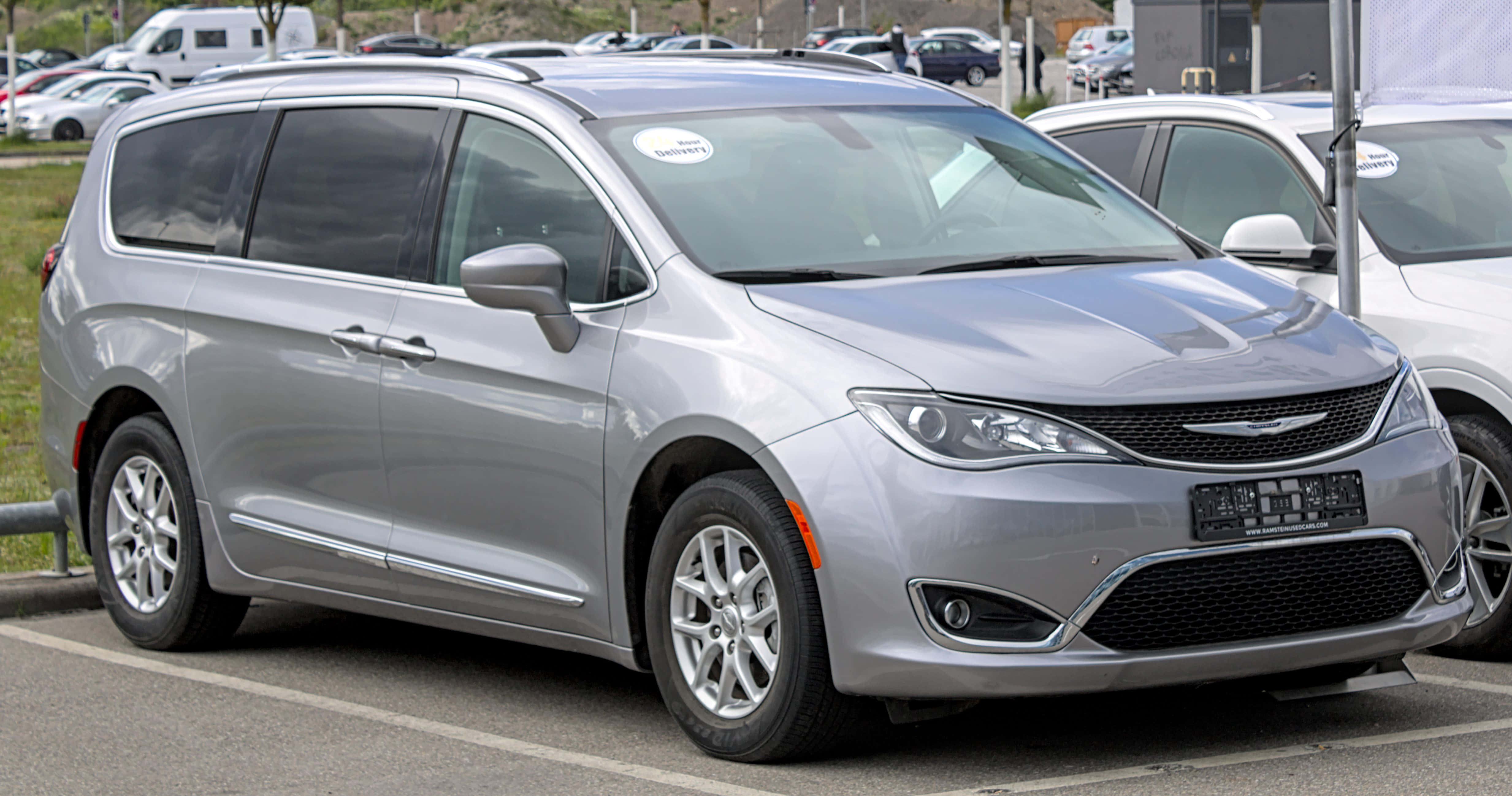 Chrysler Pacifica 桌布 壁紙 — 一架時尚的銀色 Chrysler Pacifica 小型貨車在明亮的日光下與其他汽車一起停放在停車場。