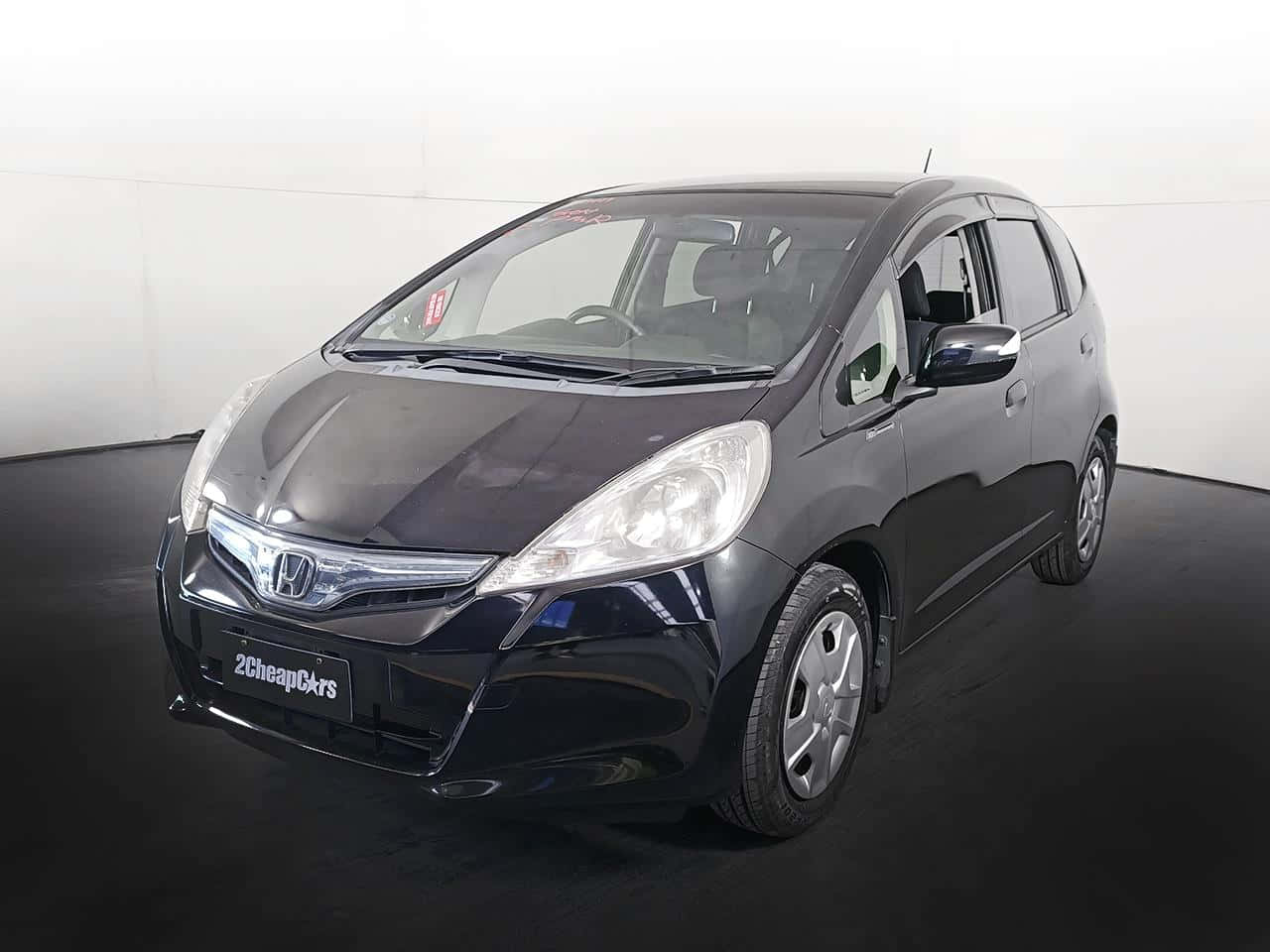 Honda Fit 桌布 壁紙 — 一架時尚黑色本田 Fit 停放在室內深色地板上，背景是純白牆壁。