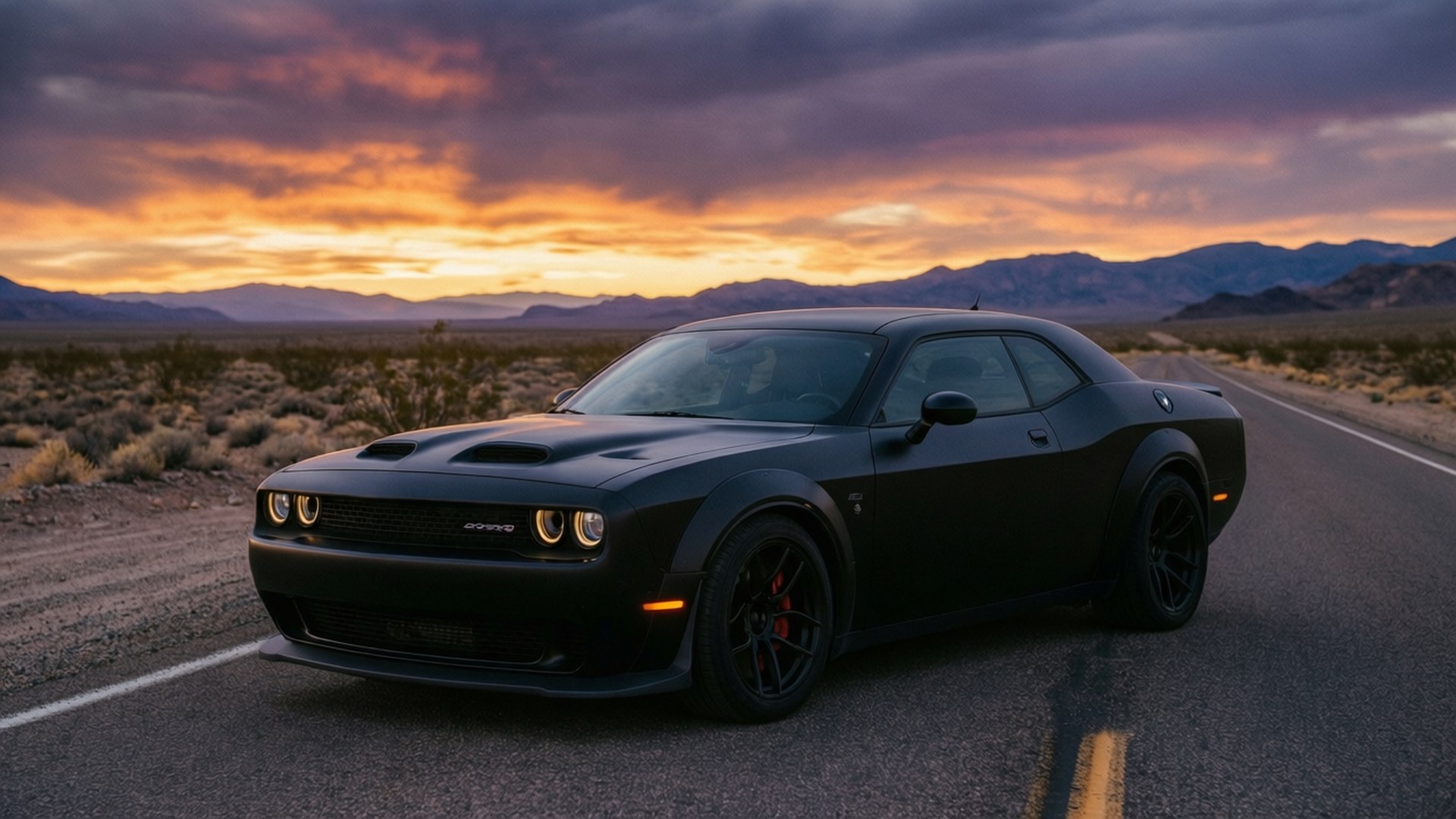桌布 壁紙 — 一架消光黑色Dodge Challenger Hellcat停放在沙漠公路上，背景是熾熱的日落天空和遠山。