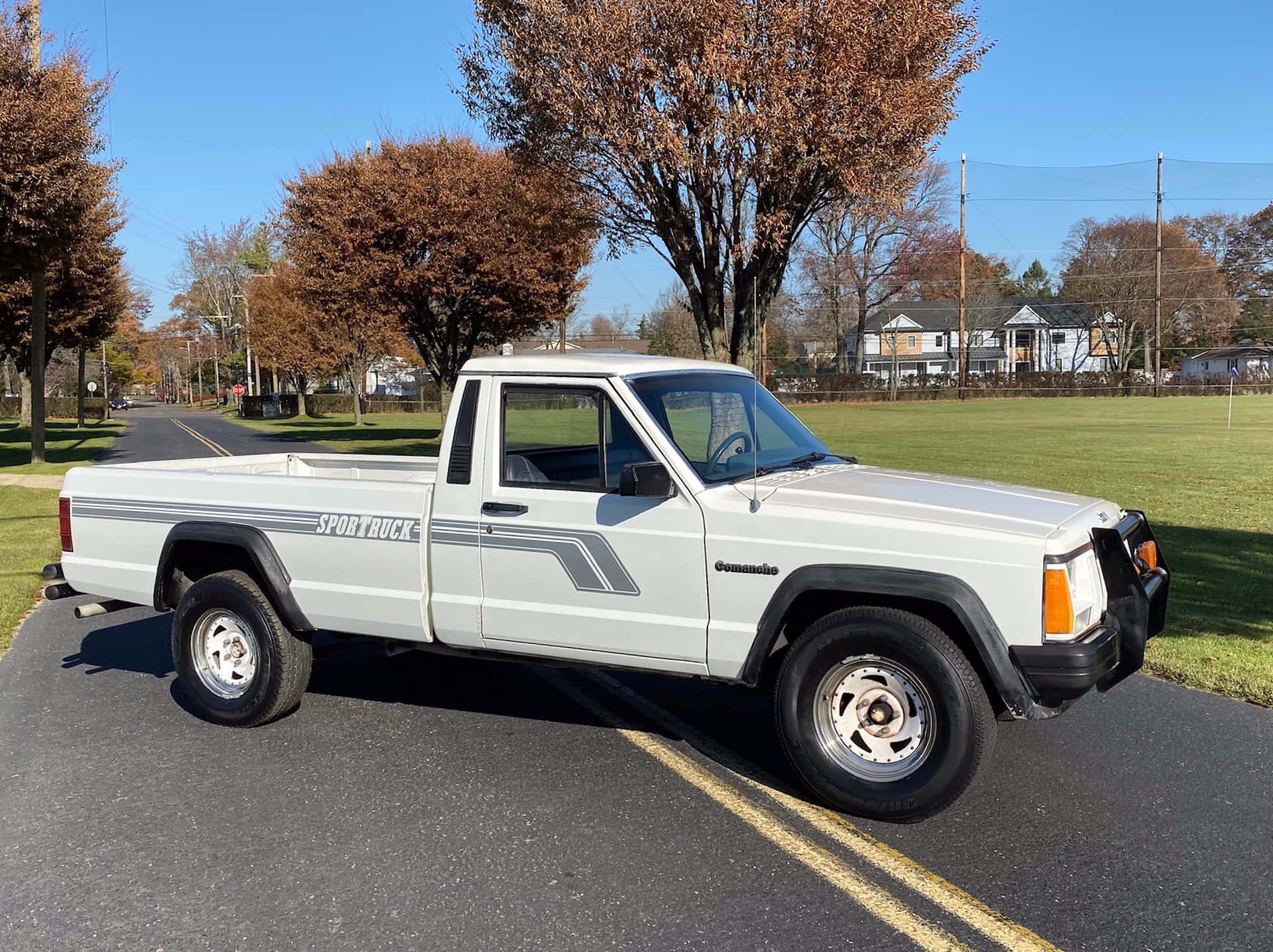 Jeep Comanche 桌布 壁紙 — 一輛白色的1980年代雪佛蘭S-10 Blazer Sport Truck停泊在陽光明媚的郊區街道上，背景有秋樹和房屋。