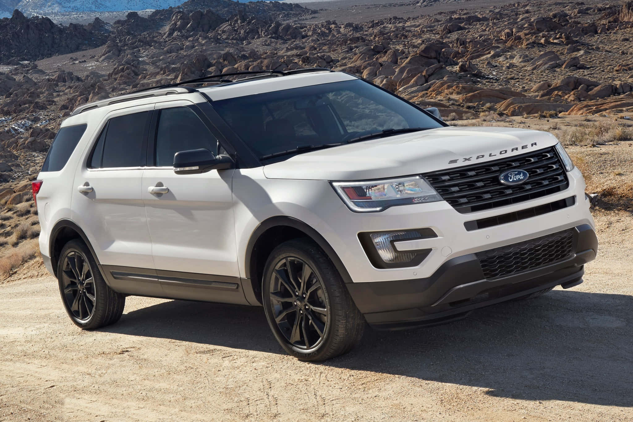Ford Explorer 桌布 壁紙 — 一輛白色福特Explorer SUV停放在塵土飛揚的沙漠道路上，背景是岩石地形，在明亮的日光下。