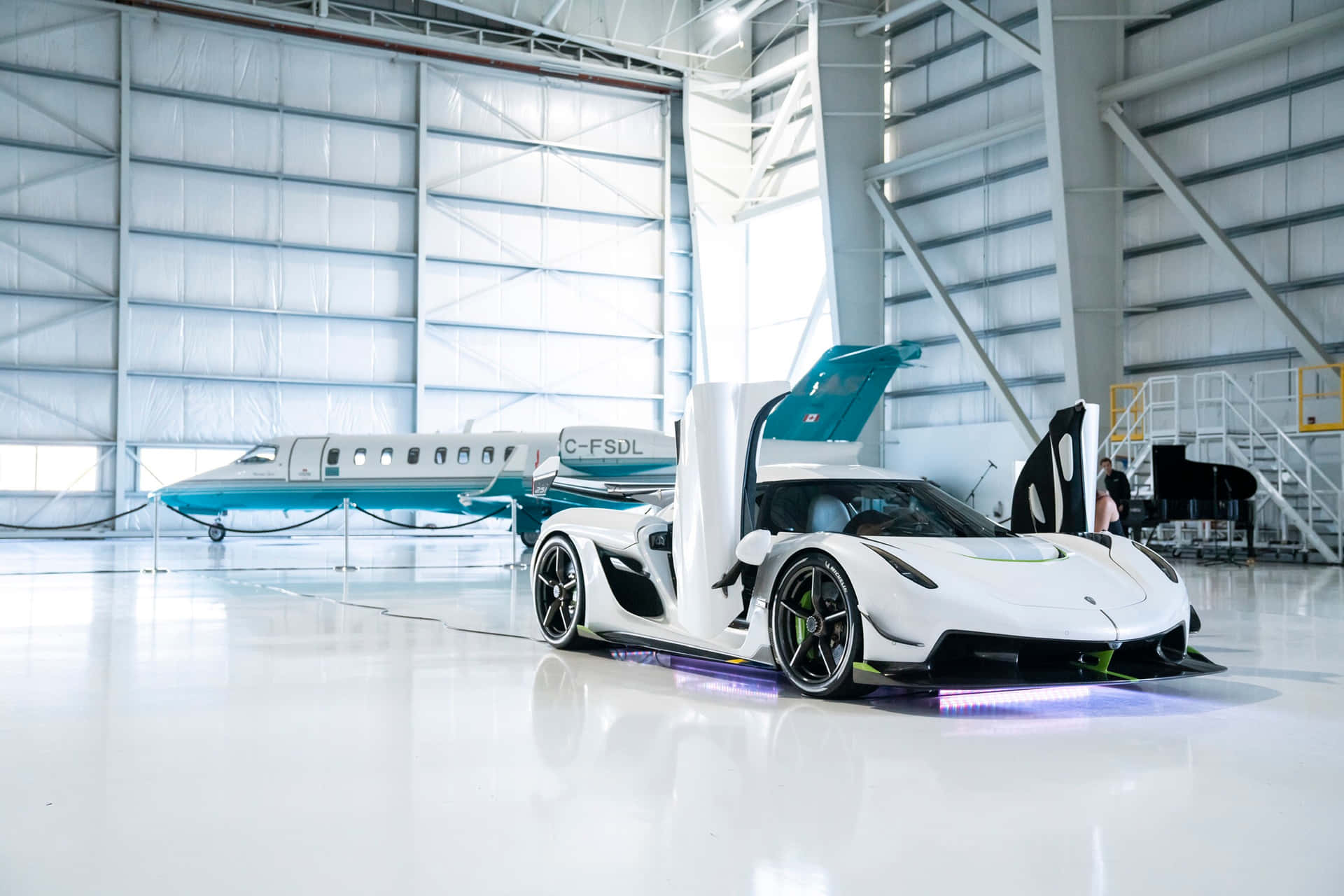  壁紙 — 一輛白色 Koenigsegg 超級跑車帶有發光紫色底盤燈，停放在機庫內，旁邊是一架藍綠色私人飛機。