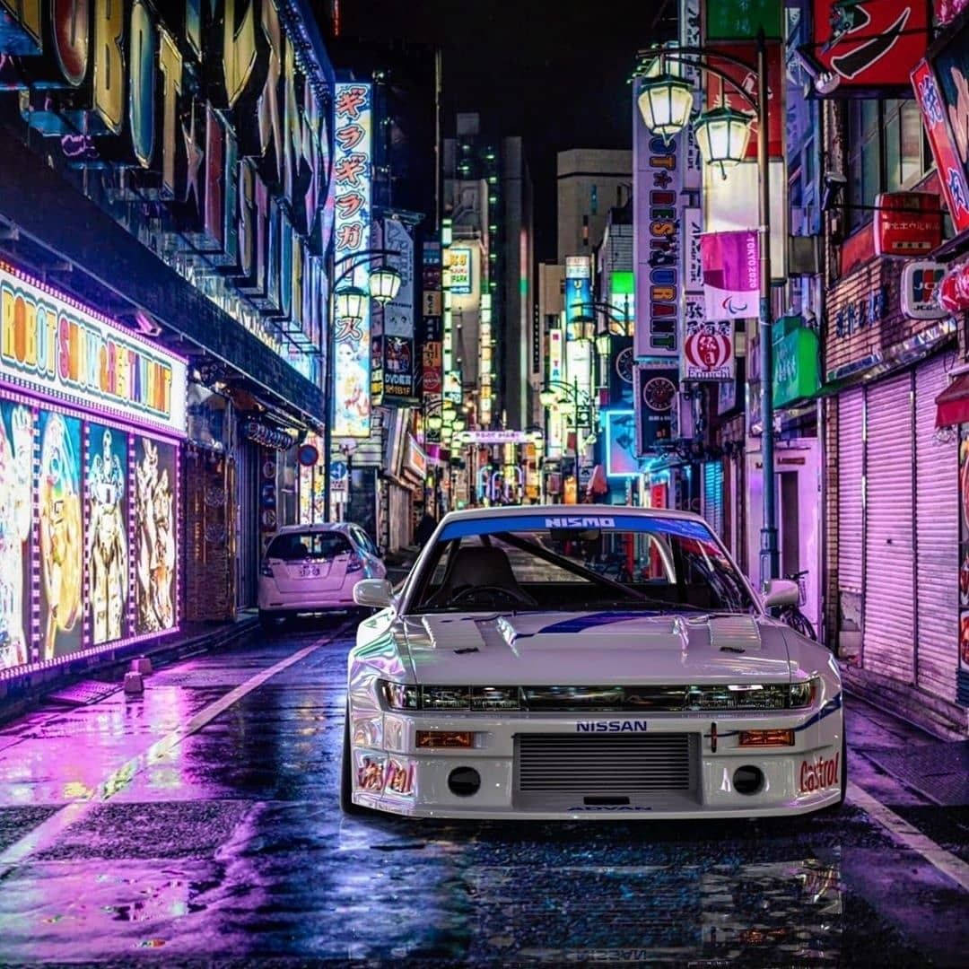 白色日產Skyline GT-R在夜晚東京濕漉漉的霓虹燈街道上 — JDM汽車 壁紙