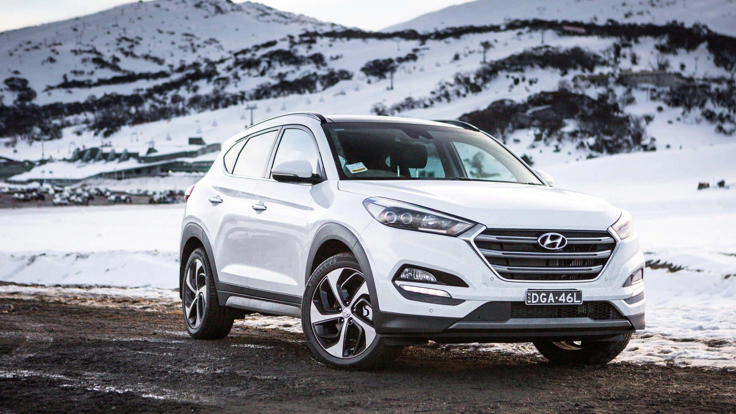 Hyundai Tucson 桌布 壁紙 — 一輛白色現代Tucson SUV停放在雪地上，背景是白雪覆蓋的山脈。