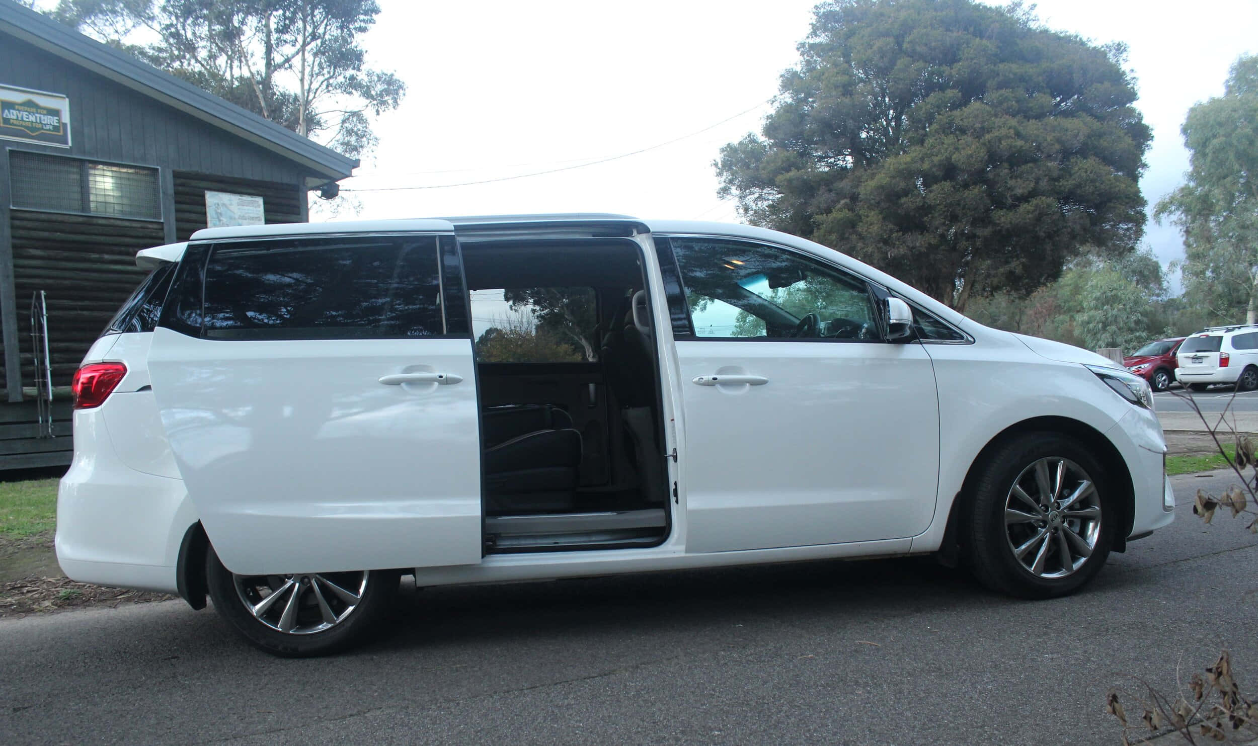 Kia Carnival 桌布 壁紙 — 一輛白色小型貨車停在街上，側門打開，露出內部。