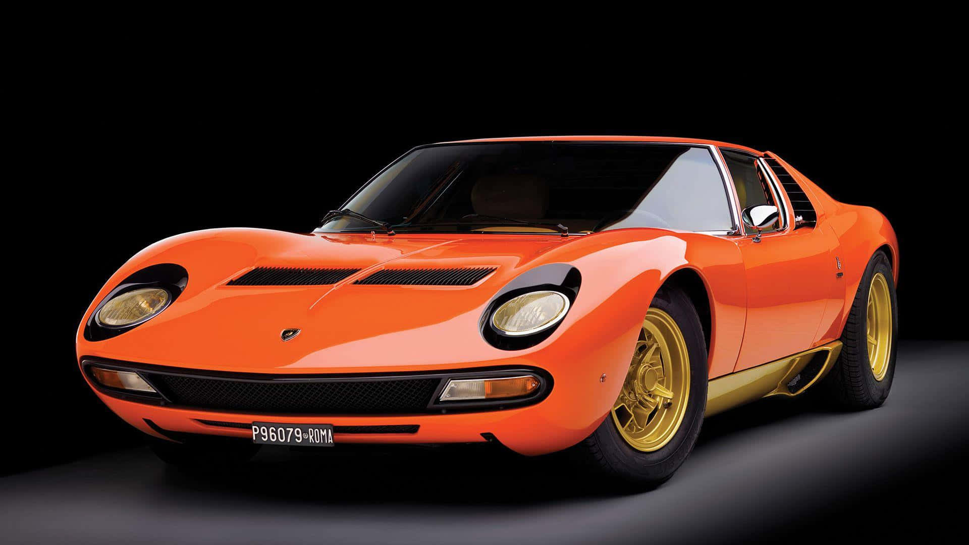 Lamborghini Miura 桌布 壁紙 — 一輛充滿活力的橘色藍寶堅尼Miura跑車，配備金色輪圈，在純黑色工作室背景前蓄勢待發。