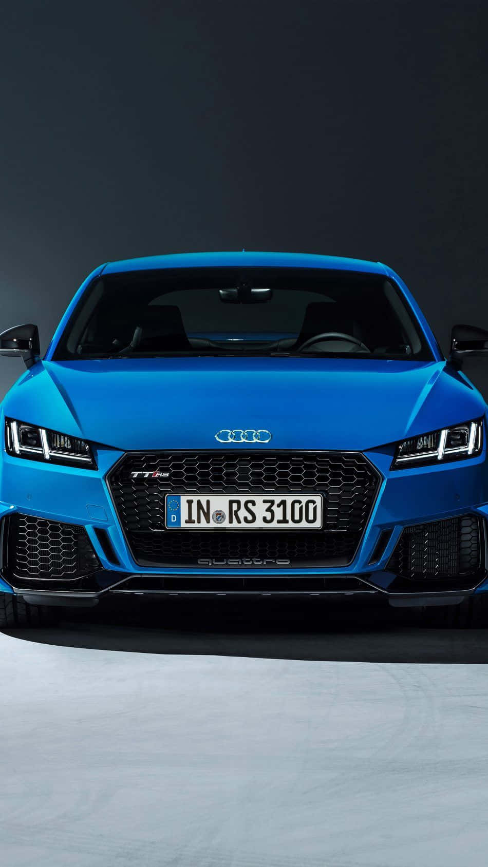 Audi Tt Rs 桌布 壁紙 — 一輛充滿活力的藍色奧迪RS 3100跑車在黑暗的攝影棚背景下以戲劇性燈光正面展示。